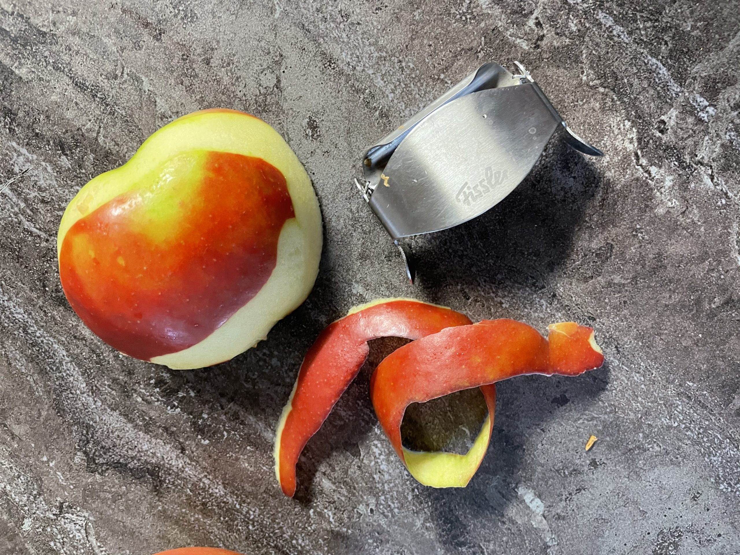 Bild zum Schritt 5 für das Bastel- und DIY-Abenteuer für Kinder: 'Schält nun von einer Hälfte des Apfels einen langen Streifen...'