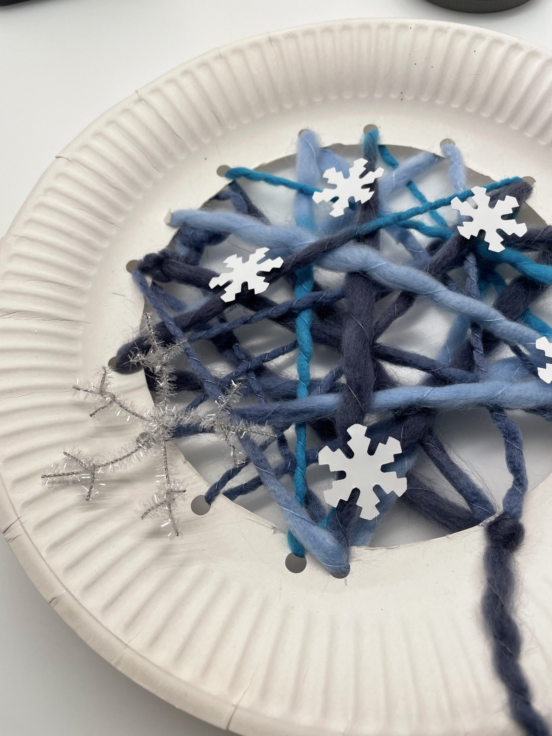 Bild zum Schritt 22 für das Bastel- und DIY-Abenteuer für Kinder: 'Dekoriert das Fadennetz mit unterschiedlichen Schneekristallen, Perlen, Federn und Kugeln....'