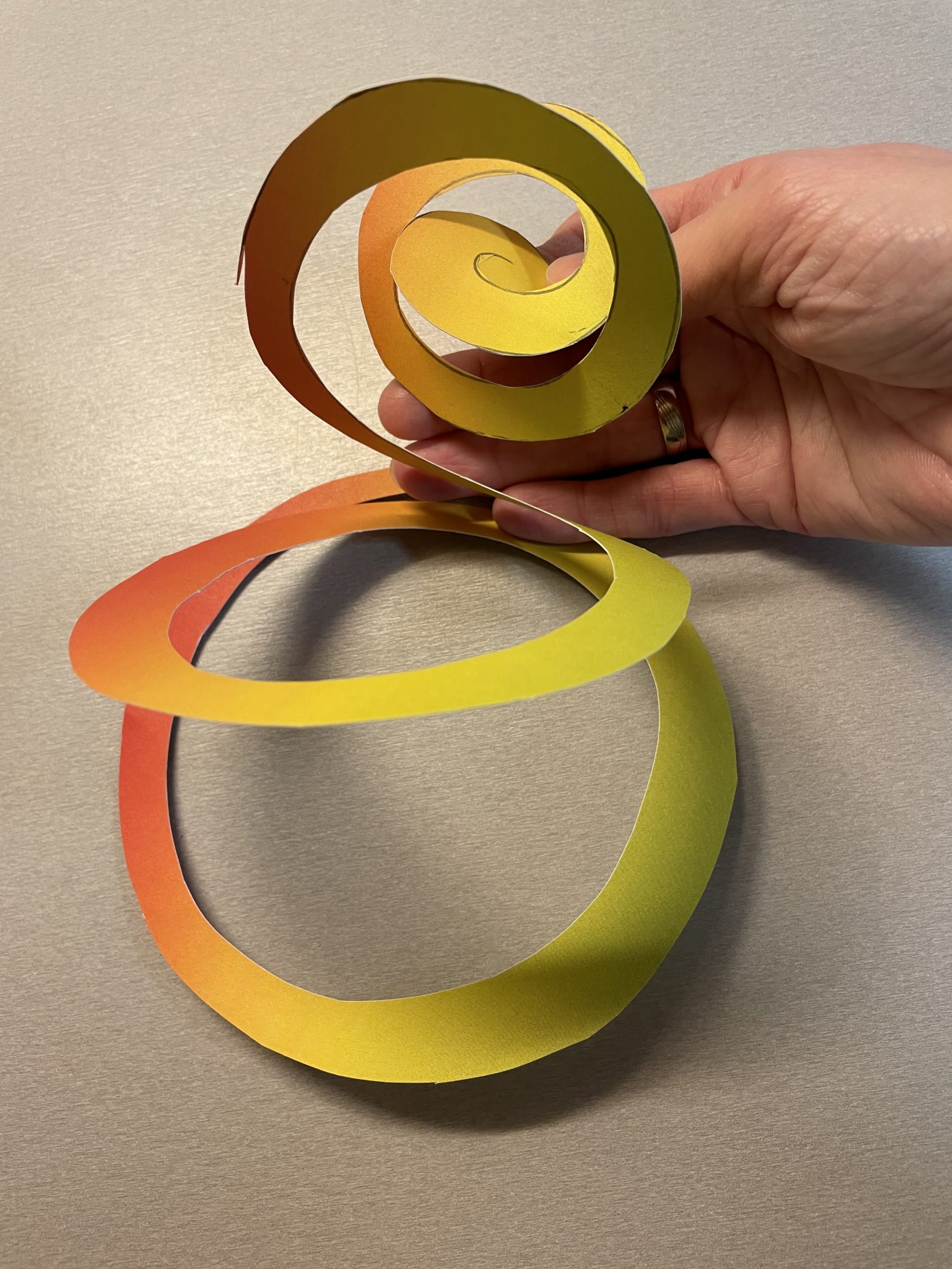 Bild zum Schritt 7 für das Bastel- und DIY-Abenteuer für Kinder: 'Hängt die Spirale am mittleren Punkt auf. So hängt sie...'