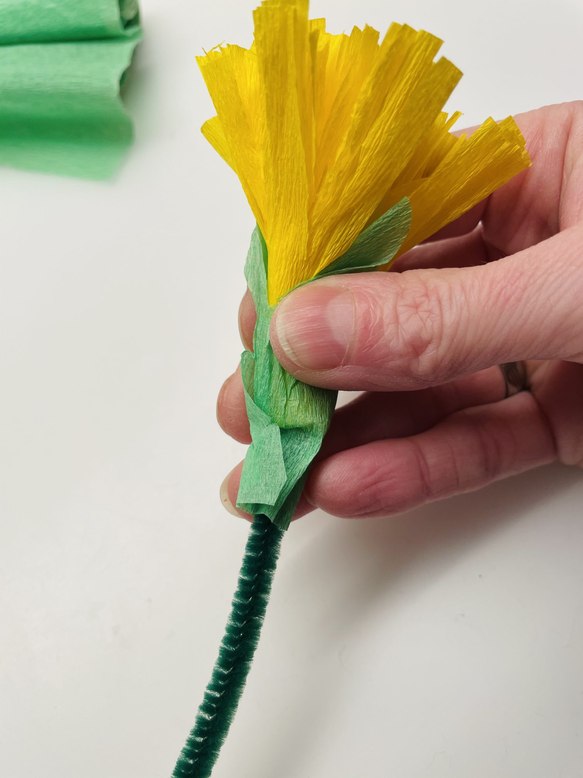 Bild zum Schritt 20 für das Bastel- und DIY-Abenteuer für Kinder: 'Steckt jetzt von unten einen Pfeifenputzer in das Blütenbündel und...'