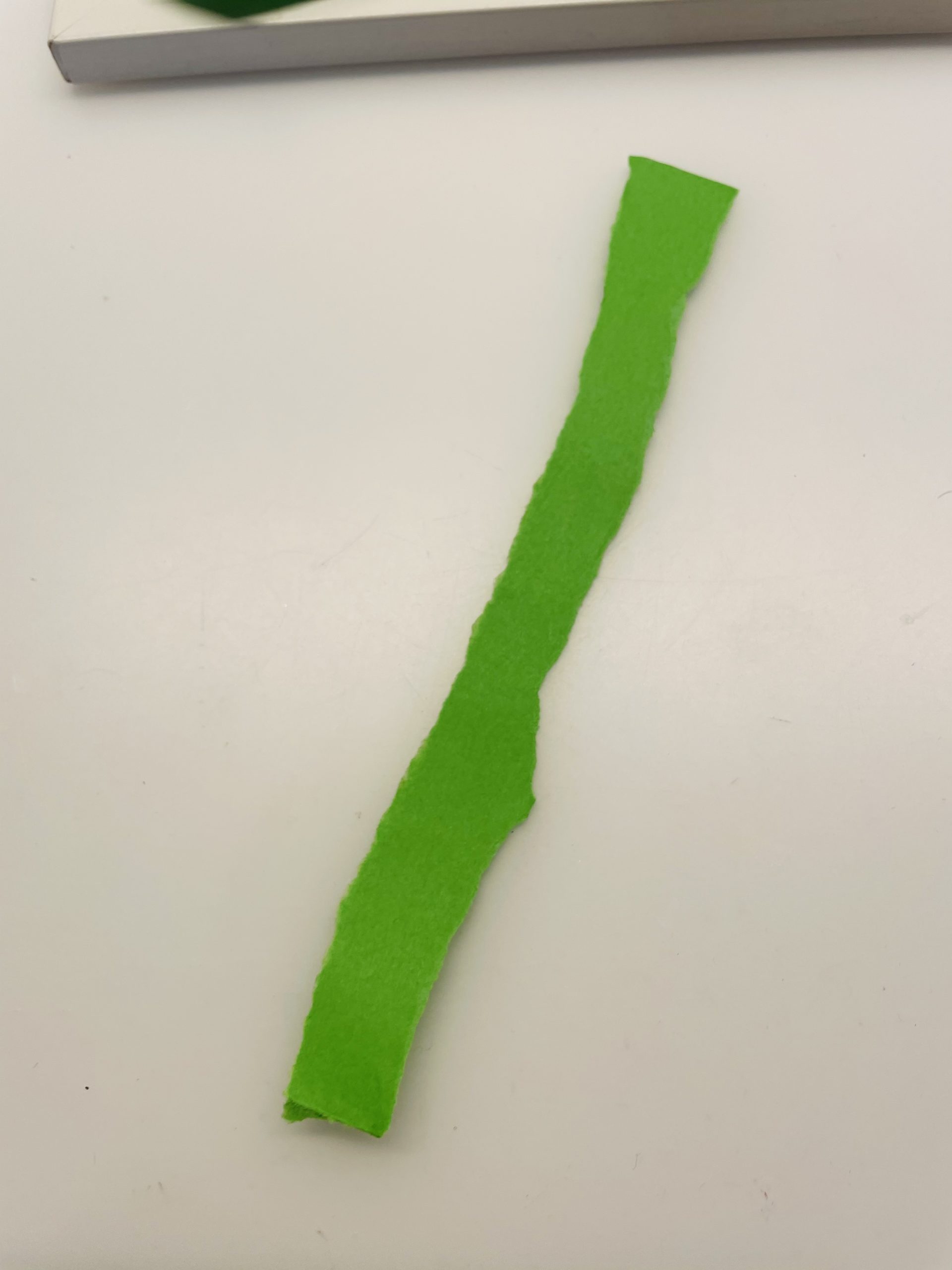Bild zum Schritt 15 für das Bastel- und DIY-Abenteuer für Kinder: 'Reißt einen weiteren Streifen grünes Papier ab (1cm breit). ...'