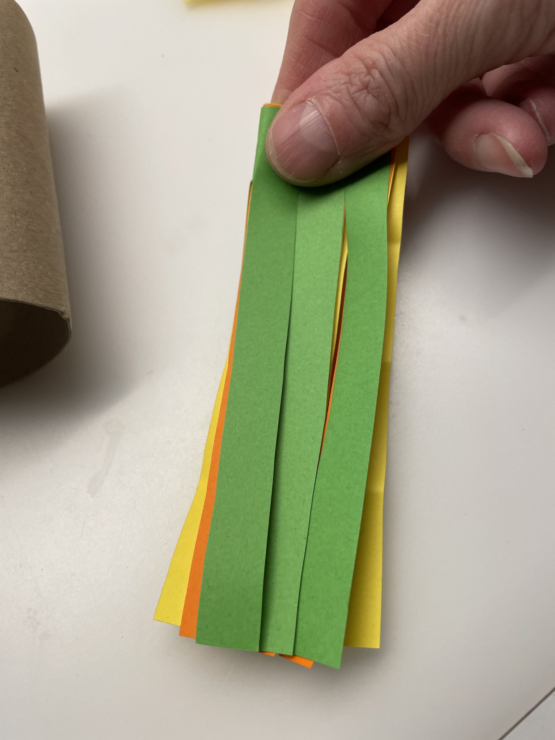 Bild zum Schritt 5 für die Kinder-Beschäftigung: 'Faltet nun das geschnittene Papier der Länge nach zusammen.'