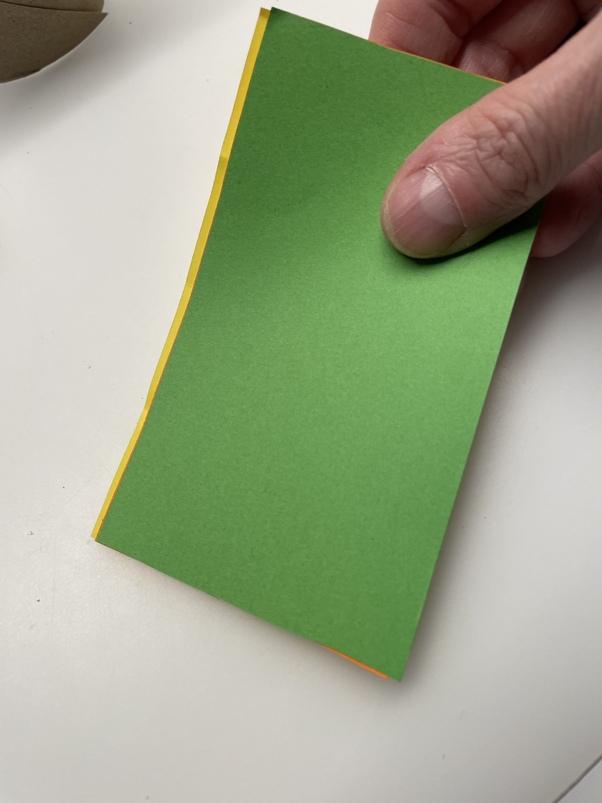 Bild zum Schritt 3 für das Bastel- und DIY-Abenteuer für Kinder: 'Anschließend legt ihr das gelbe, orange und grüne Papier aufeinander....'