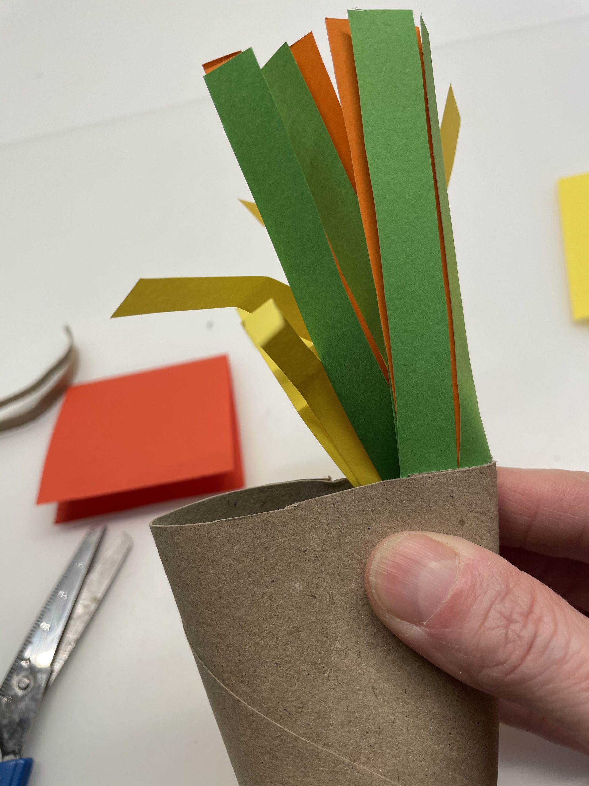Bild zum Schritt 7 für das Bastel- und DIY-Abenteuer für Kinder: 'Anschließend drückt ihr die Papprolle so zusammen, dass der Papierstreifen...'
