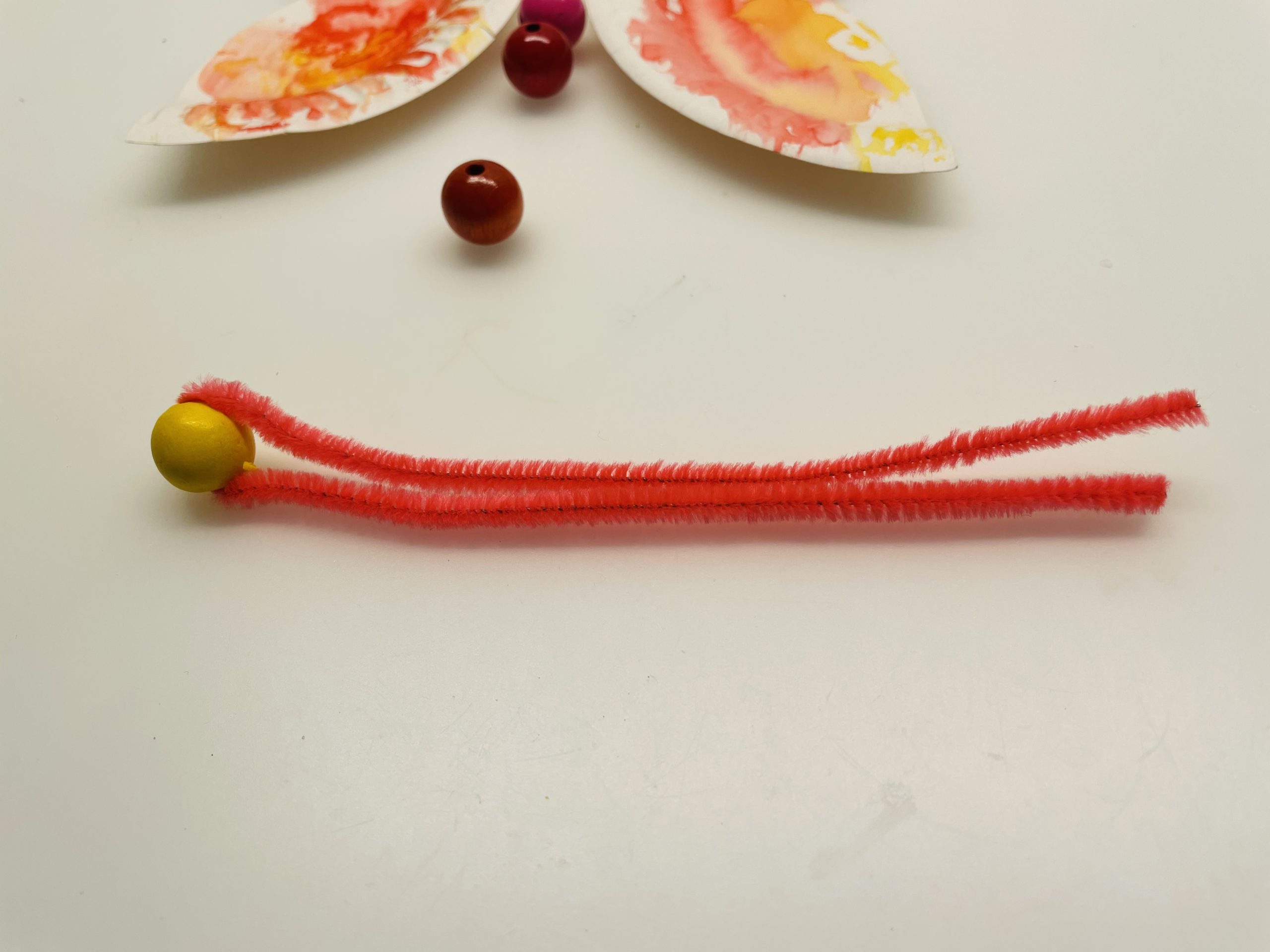 Bild zum Schritt 24 für das Bastel- und DIY-Abenteuer für Kinder: '[Eltern]Steckt zuerst eine Perle auf den Pfeifenputzer und schiebt sie...'