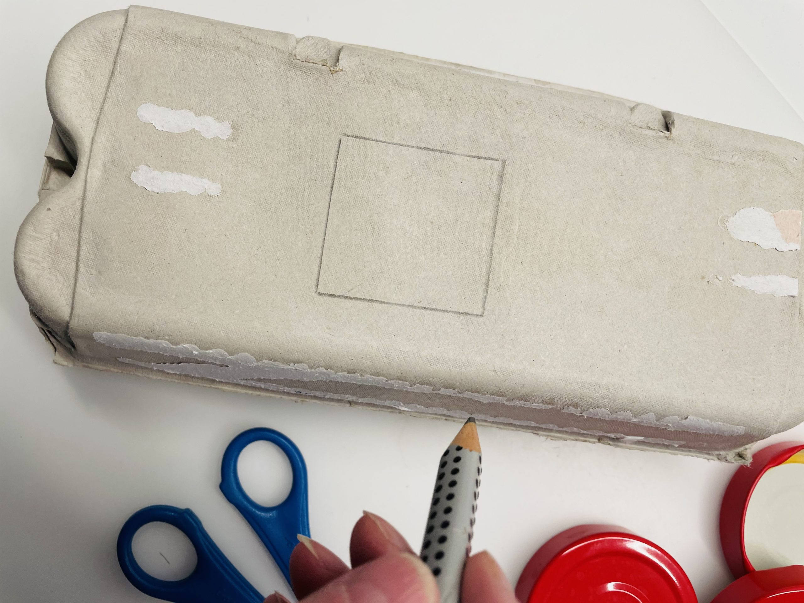 Bild zum Schritt 3 für das Bastel- und DIY-Abenteuer für Kinder: 'Malt zuerst auf den Schachteldeckel des Eierkartons ein Viereck.'
