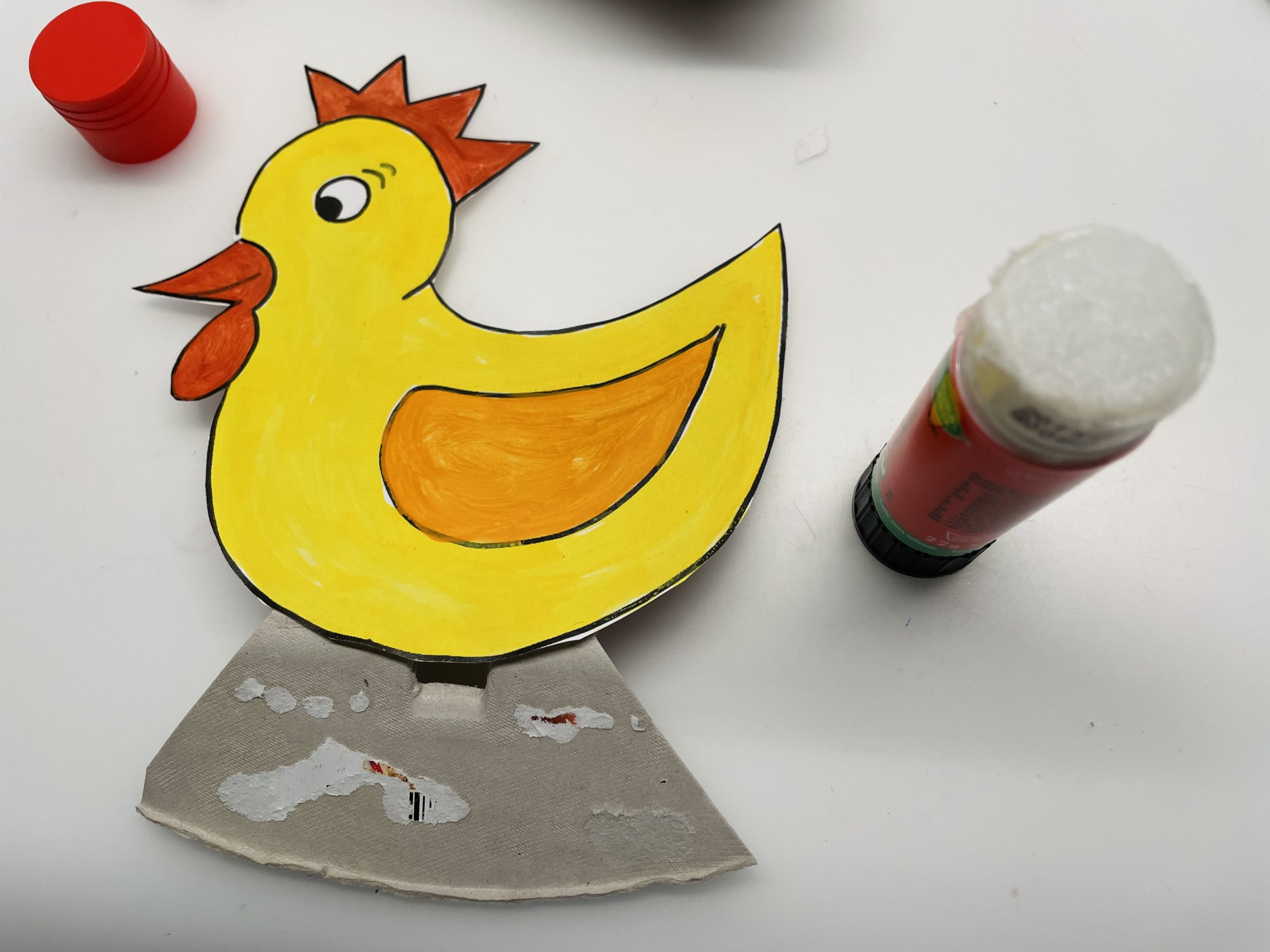 Bild zum Schritt 13 für das Bastel- und DIY-Abenteuer für Kinder: 'Anschließend klebt ihr das Huhn auf die Vorderseite auf.'