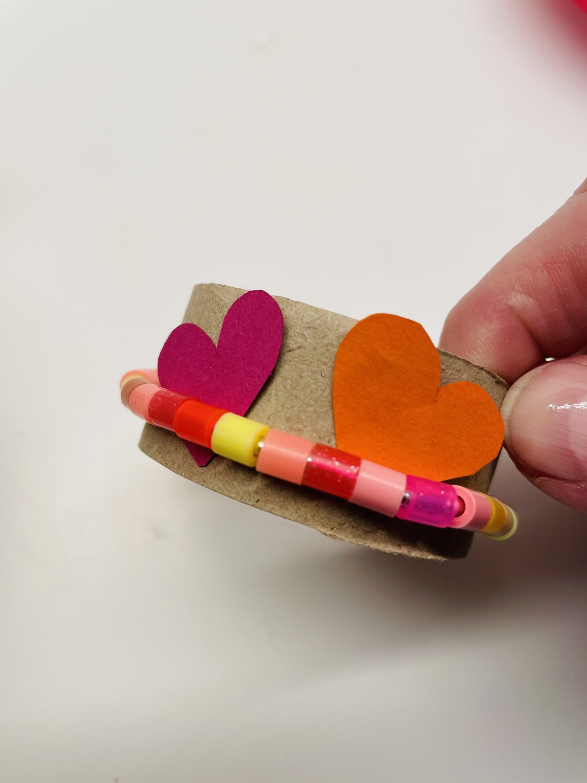 Bild zum Schritt 8 für das Bastel- und DIY-Abenteuer für Kinder: 'Anschließend legt ihr die Herzen zwischen Perlenring und Papprolle.'