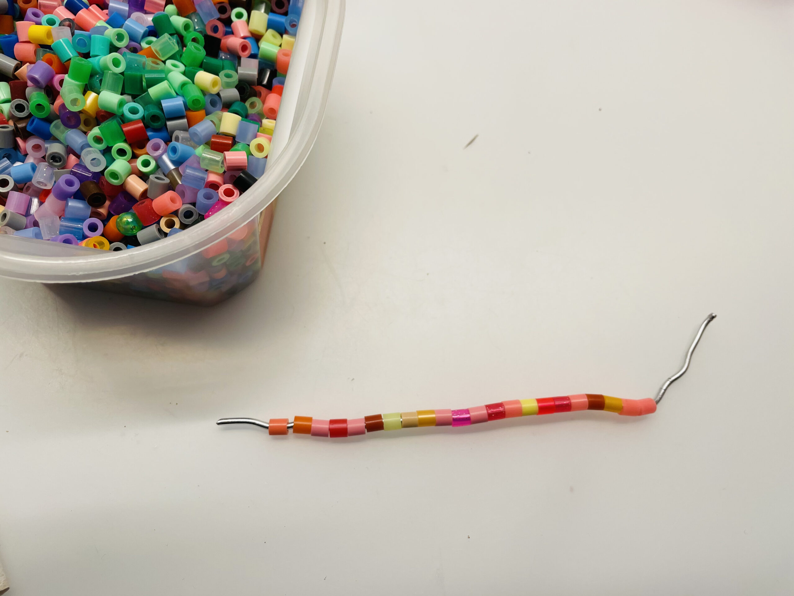 Bild zum Schritt 3 für das Bastel- und DIY-Abenteuer für Kinder: 'Füllt den kompletten Draht mit Perlen. Schiebt sie lückenlos zusammen.'