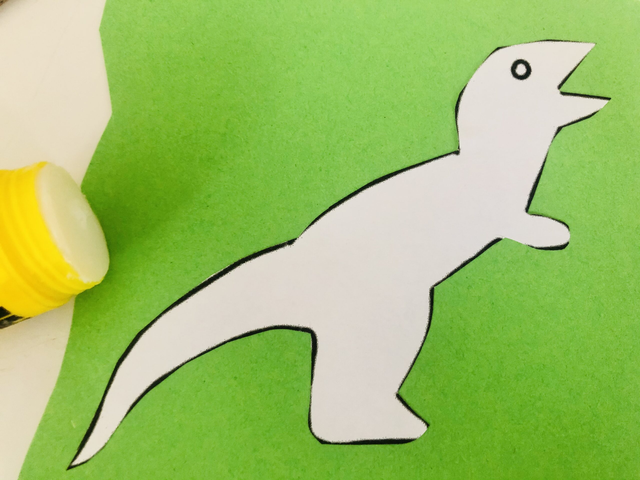 Bild zum Schritt 3 für das Bastel- und DIY-Abenteuer für Kinder: 'Jetzt klebt ihr die Dinos auf ein Stück farbiges Tonpapier.'