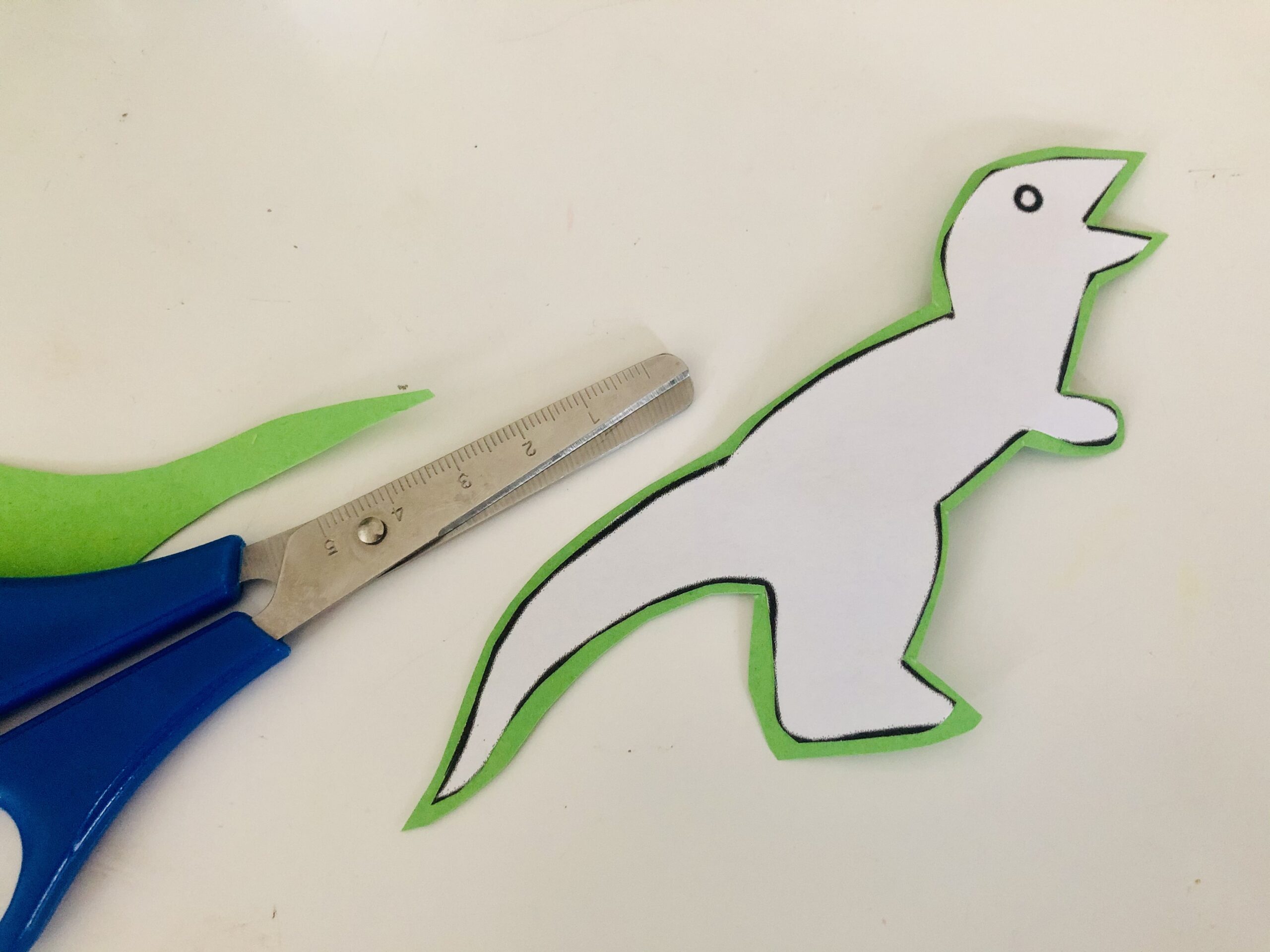 Bild zum Schritt 4 für das Bastel- und DIY-Abenteuer für Kinder: 'Schneidet den Dinosaurier erneut zu. Lasst dabei rundherum einen kleinen...'