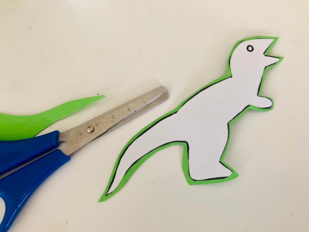 Bild zum Schritt 5 für das Bastel- und DIY-Abenteuer für Kinder: 'Schneidet dann den Dino wieder aus. Lasst dabei aber einen...'