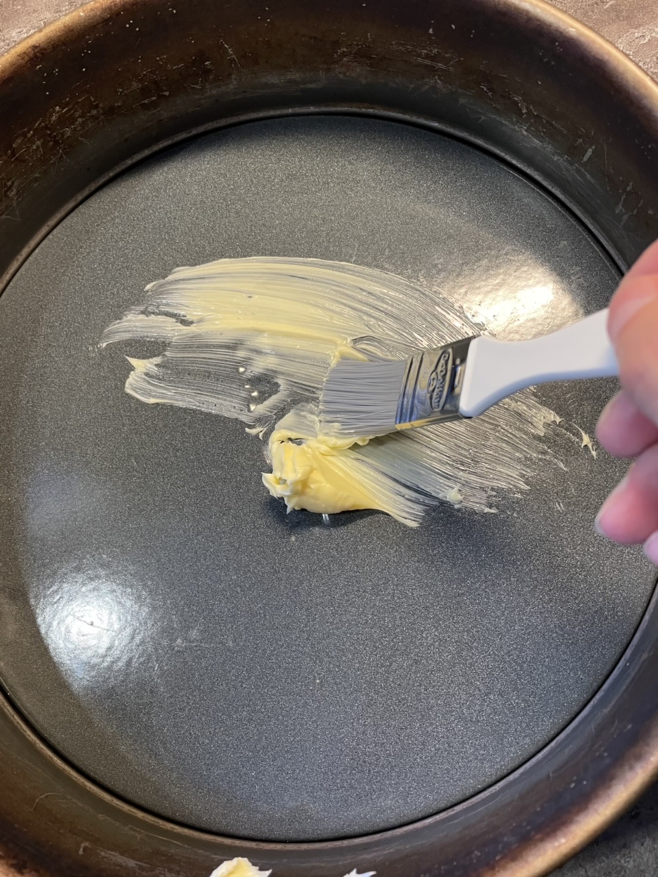 Bild zum Schritt 4 für das Bastel- und DIY-Abenteuer für Kinder: 'Verteilt anschließend einen Esslöffel Margarine mit dem Pinsel am Boden...'