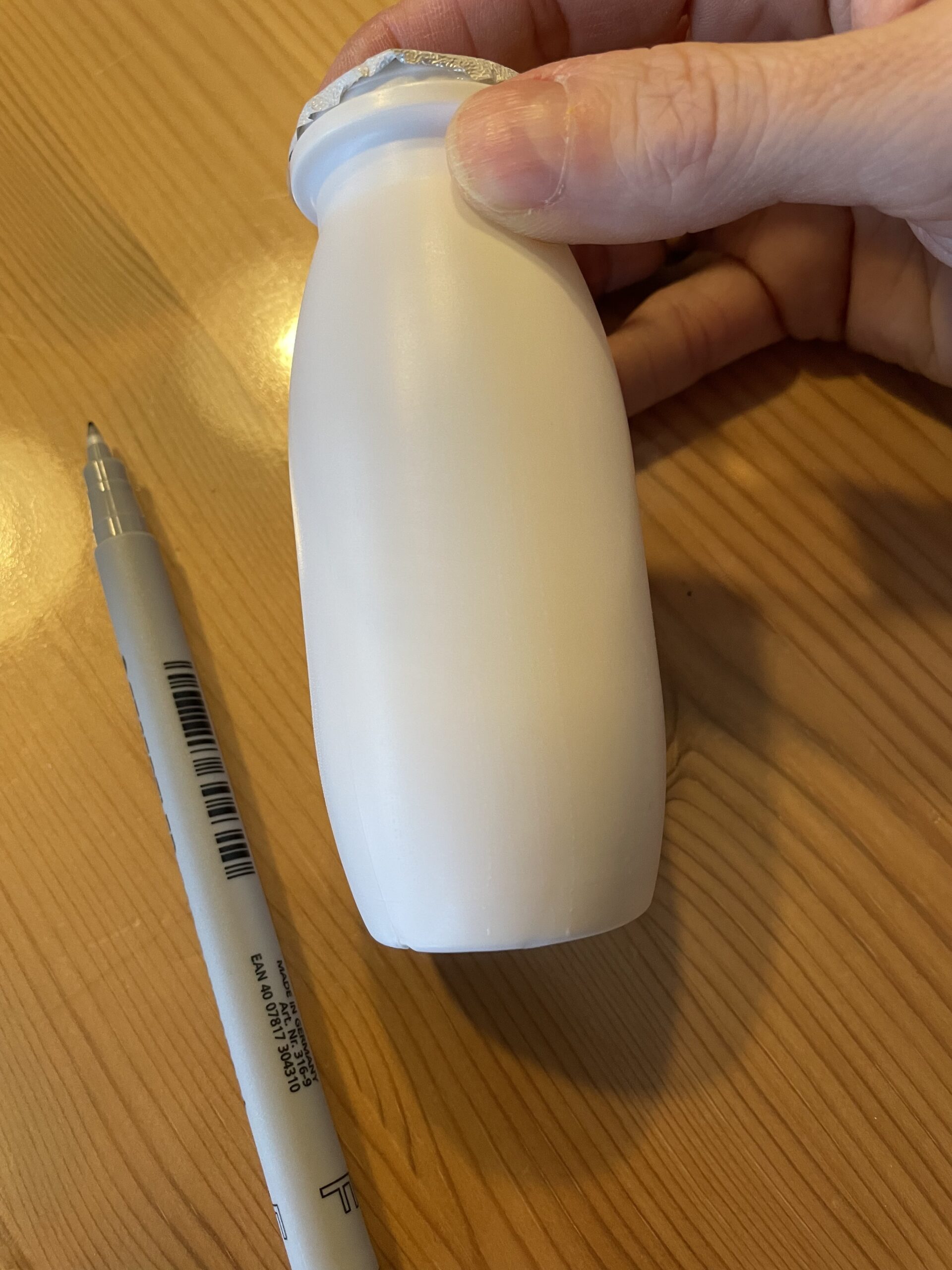 Bild zum Schritt 1 für das Bastel- und DIY-Abenteuer für Kinder: 'Zuerst entfernt ihr das Etikett von einen Trinkjoghurt. Öffnet den...'