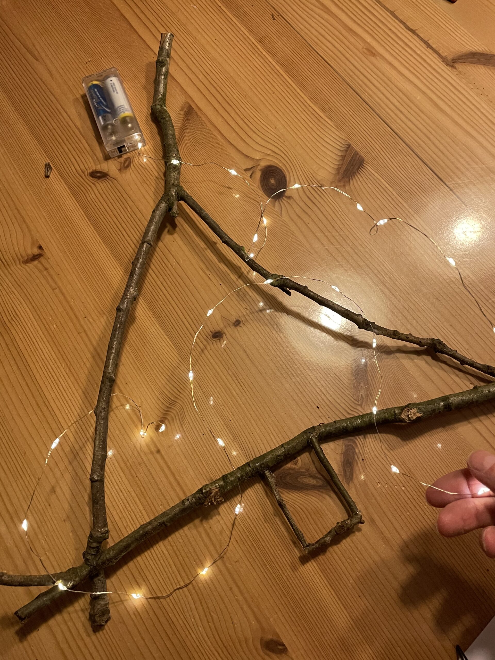 Bild zum Schritt 9 für das Bastel- und DIY-Abenteuer für Kinder: 'Jetzt wickelt ihr eine dünne Lichterketten um den Tannenbaum.'
