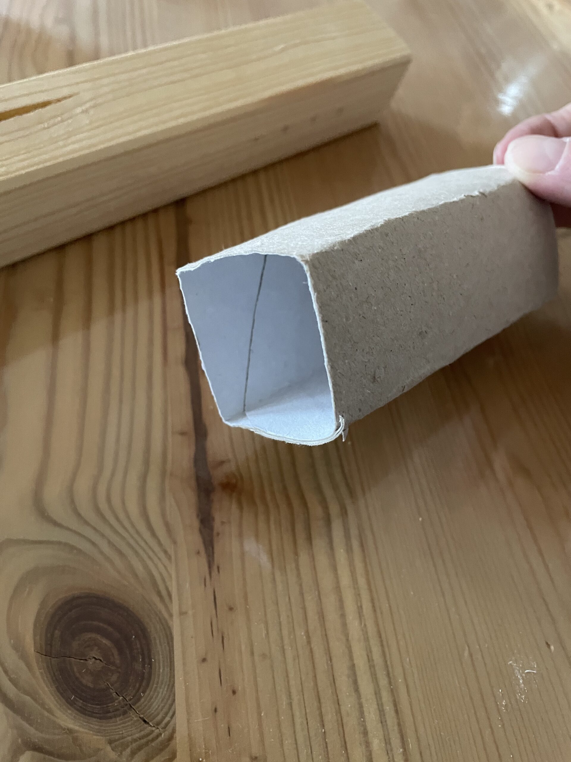 2. Bild zum Schritt 3 für das Bastel- und DIY-Abenteuer für Kinder: 'Drückt die Papprolle an die Holzkante und biegt die Rolle,...'