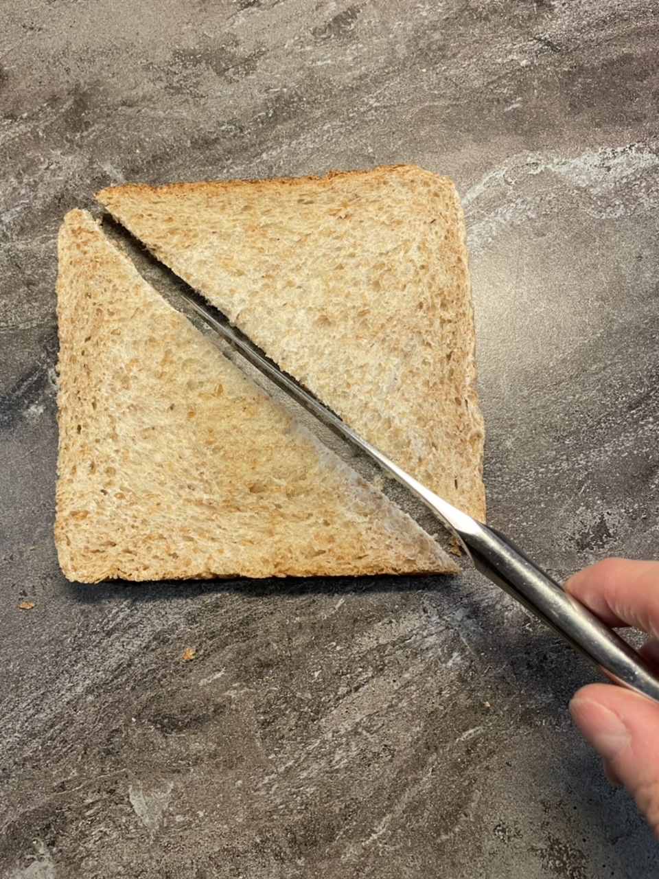Bild zum Schritt 2 für das Bastel- und DIY-Abenteuer für Kinder: 'Schneidet das Toastbrot zuerst diagonal in der Mitte durch.'