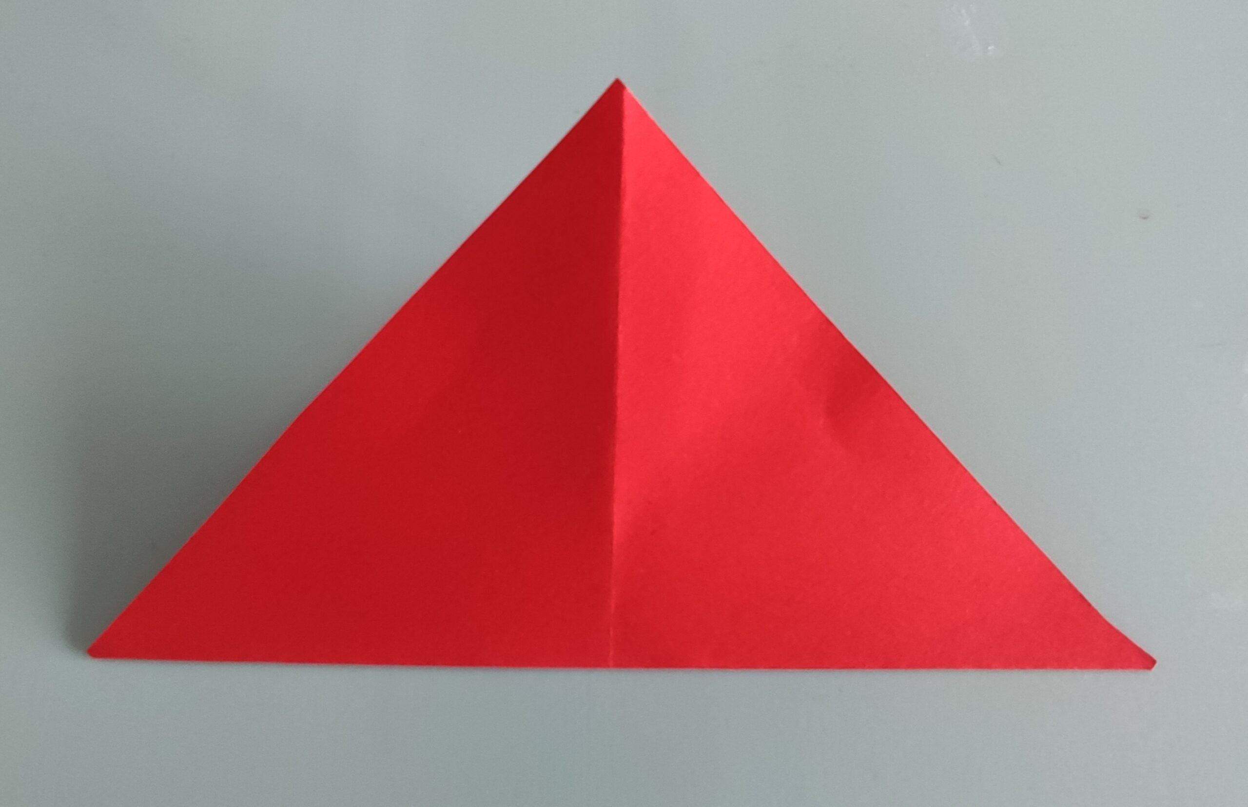 Bild zum Schritt 4 für das Bastel- und DIY-Abenteuer für Kinder: 'Jetzt legt ihr das rote Papier mit einer Spitze auf...'