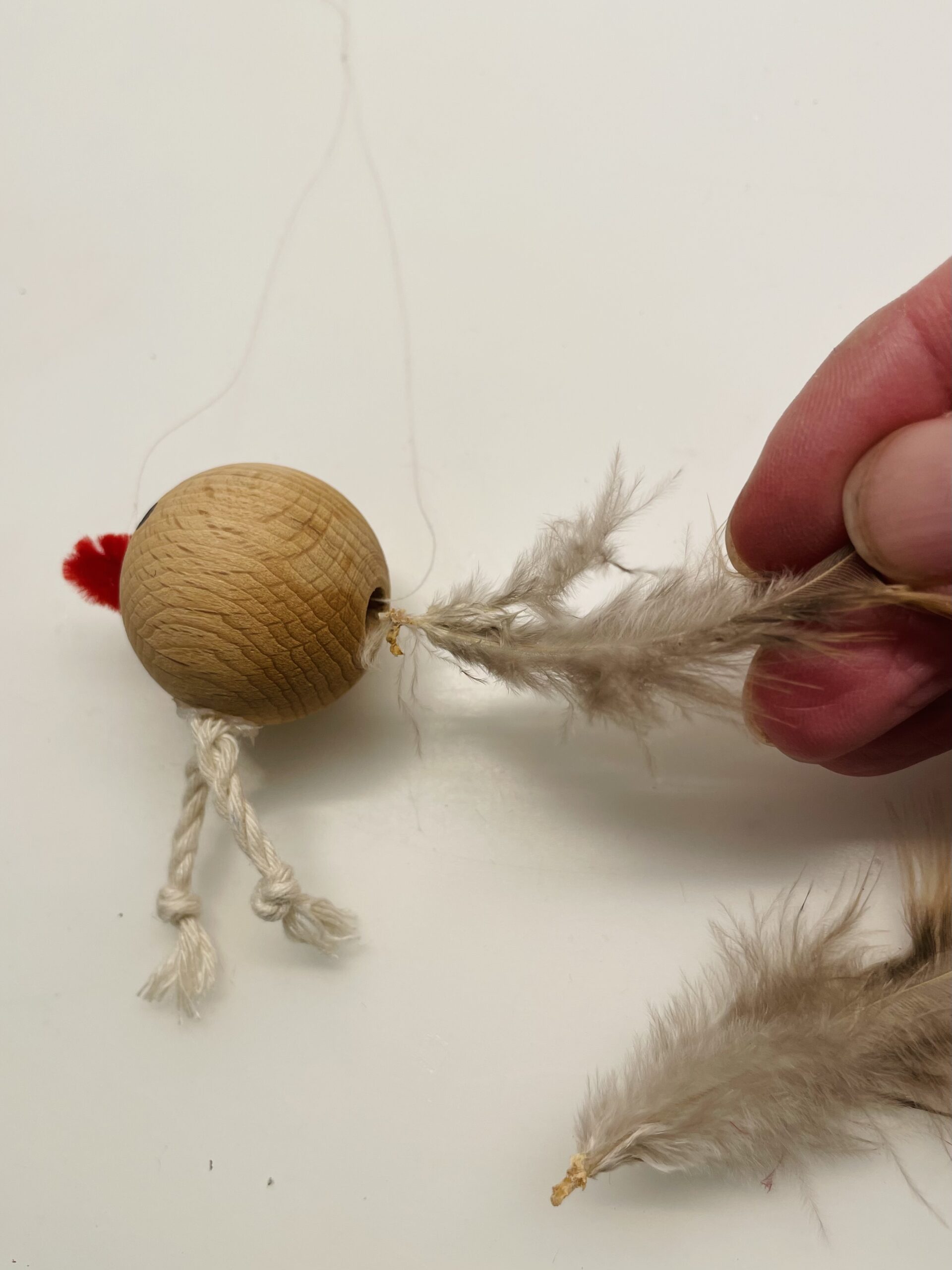 Bild zum Schritt 9 für das Bastel- und DIY-Abenteuer für Kinder: 'In das noch freie Loch der Perle werden Federn gesteckt....'