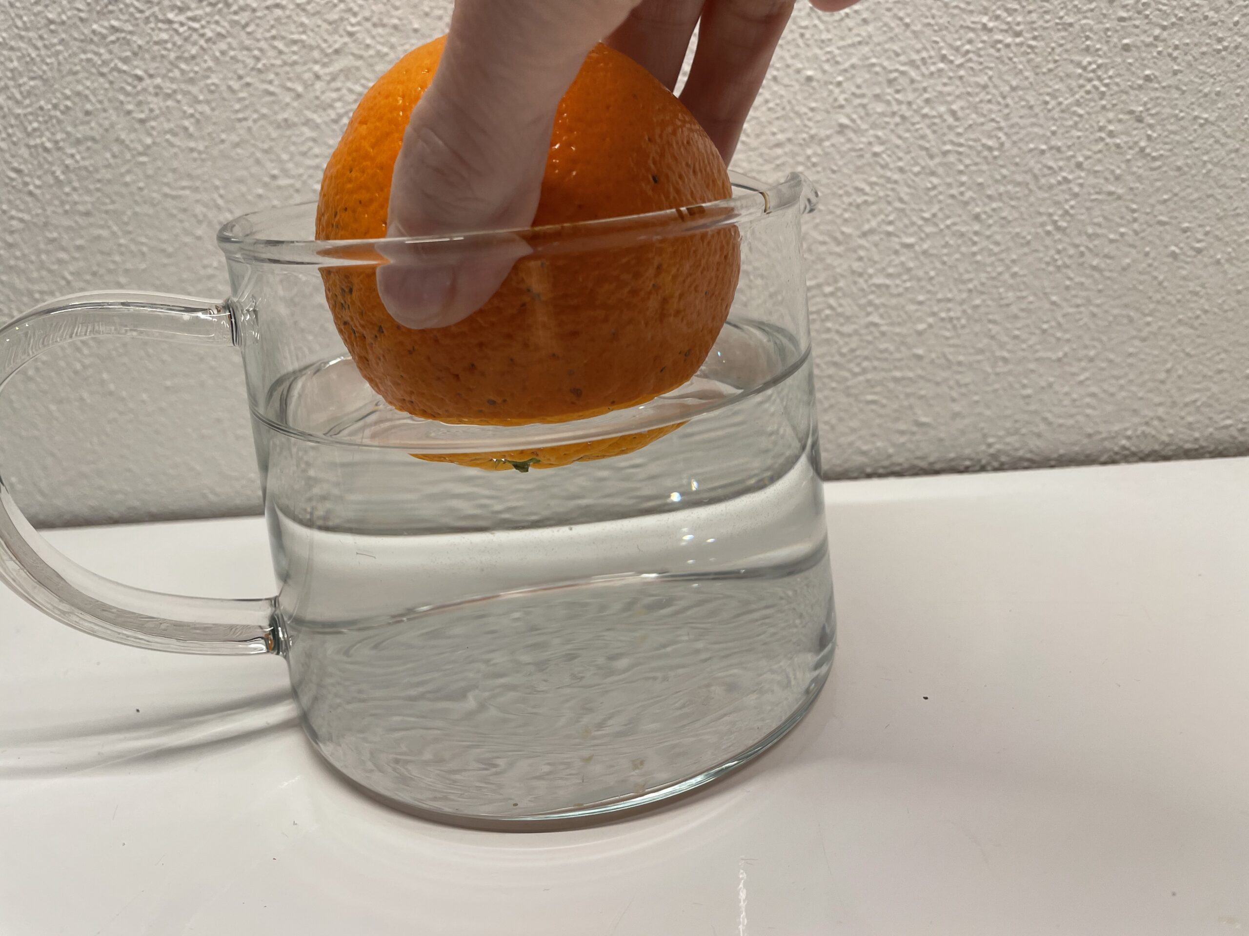Bild zum Schritt 2 für das Bastel- und DIY-Abenteuer für Kinder: 'Jetzt legt ihr die Orange langsam ins Wasser.'