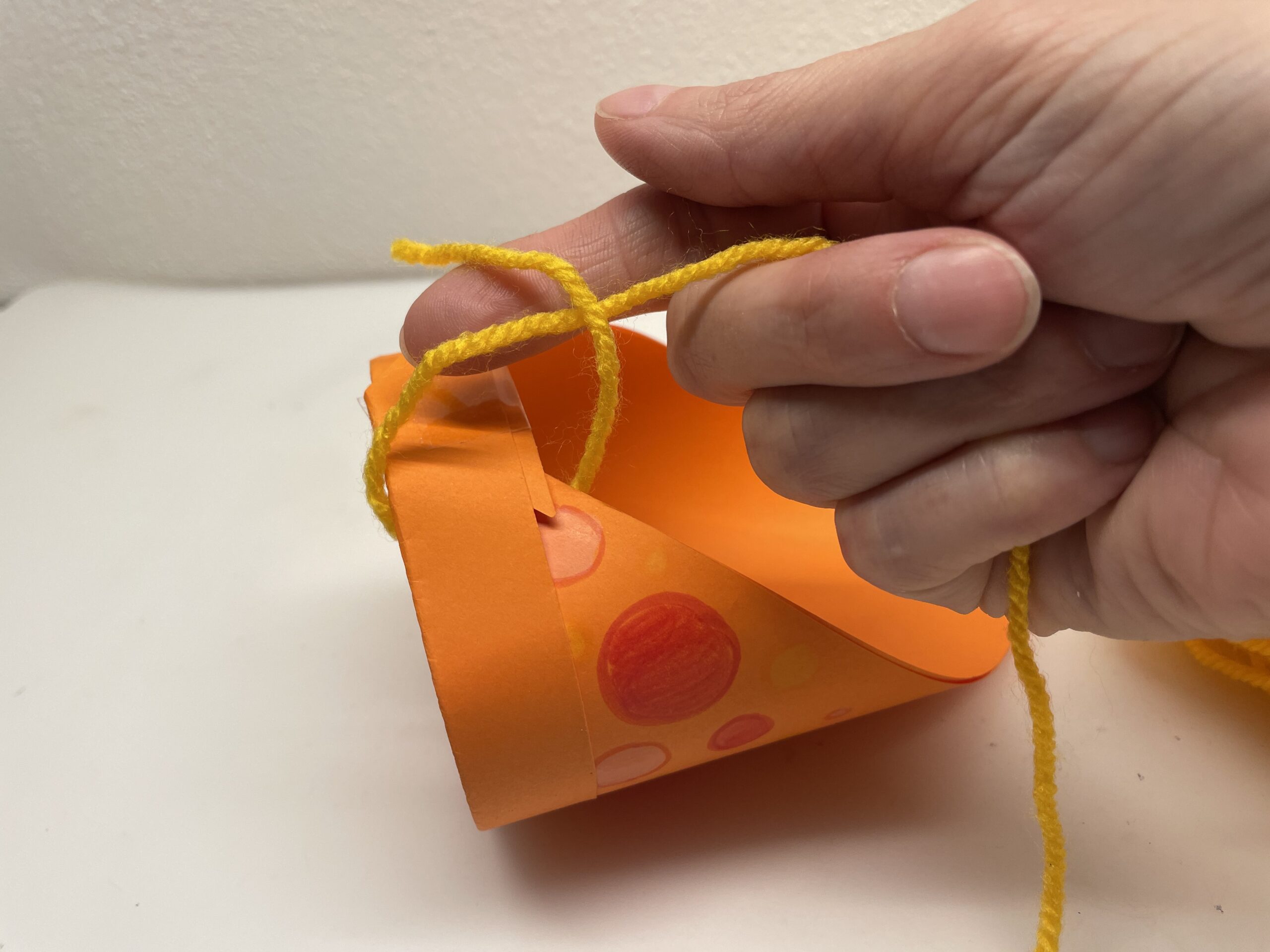 Bild zum Schritt 31 für das Bastel- und DIY-Abenteuer für Kinder: 'Steckt dazu das Fadenende durch die schmalste Stelle und legt...'