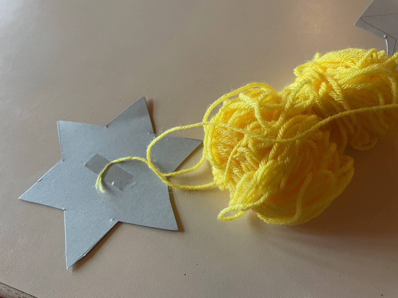 Bild zum Schritt 3 für das Bastel- und DIY-Abenteuer für Kinder: 'Nehmt gelbe Wolle und klebt den Fadenanfang mit einem Klebestreifen...'
