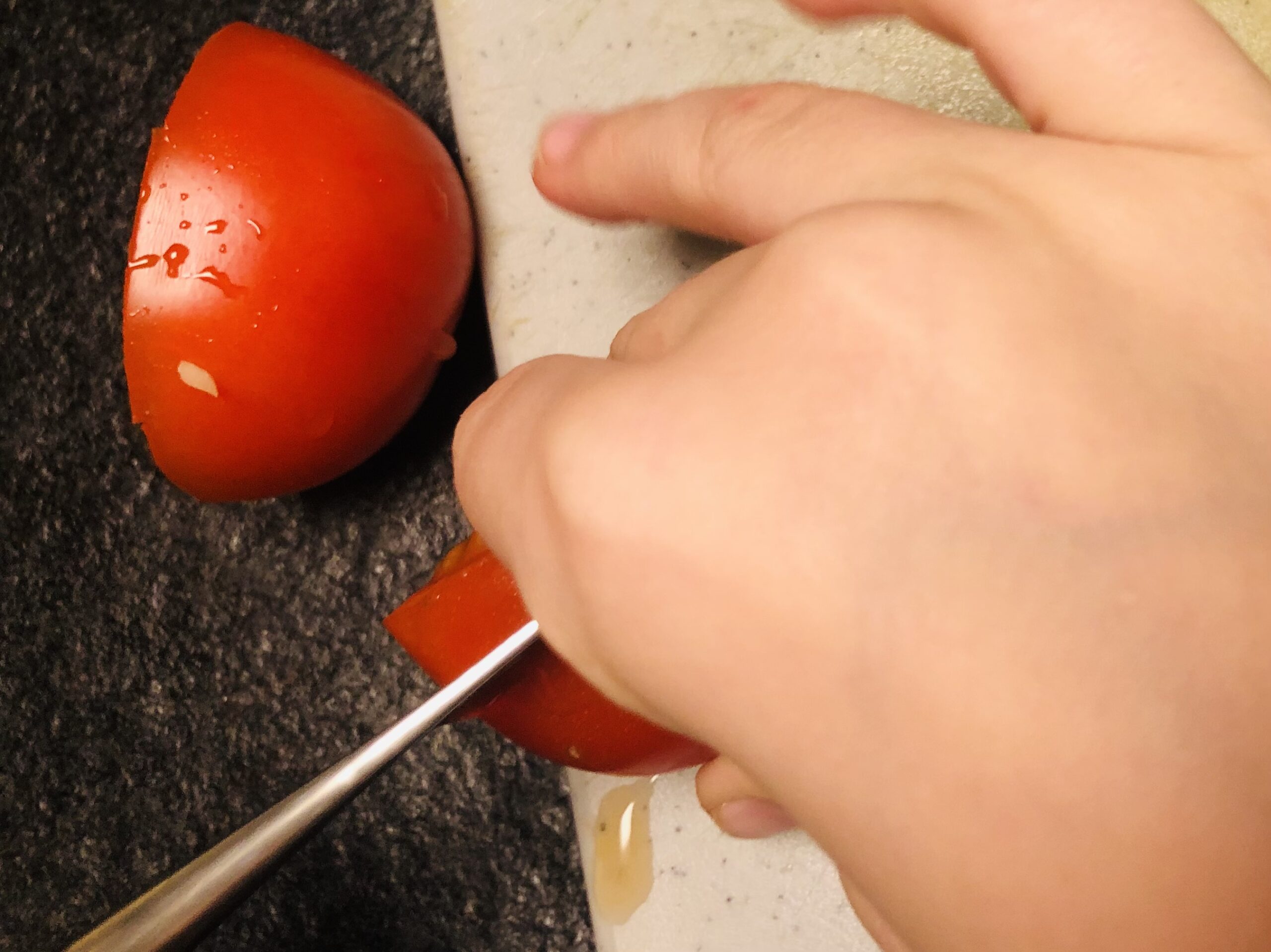 Bild zum Schritt 11 für das Bastel- und DIY-Abenteuer für Kinder: 'Danach halbiert ihr die Tomate und schneidet sie in dicke...'