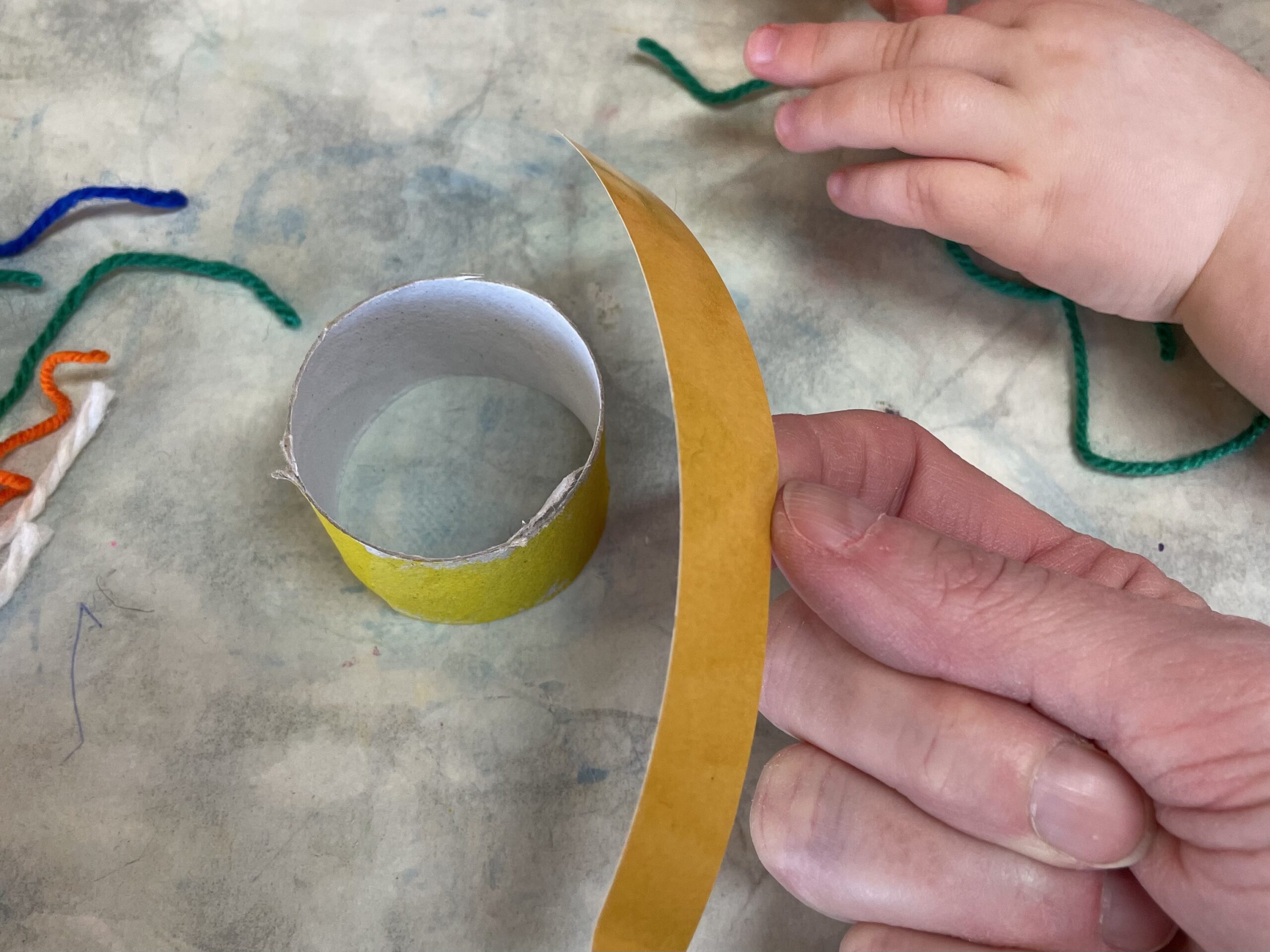 Bild zum Schritt 7 für das Bastel- und DIY-Abenteuer für Kinder: 'Schneidet einen  Streifen doppelseitiges Klebeband mit der Schere ab....'