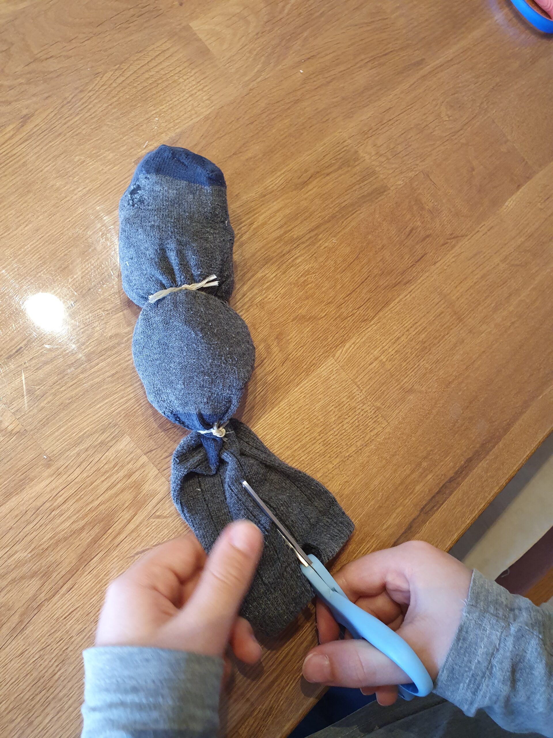 Bild zum Schritt 5 für das Bastel- und DIY-Abenteuer für Kinder: 'Jetzt schneidet ihr das obere Stück der Socke, indem keine...'