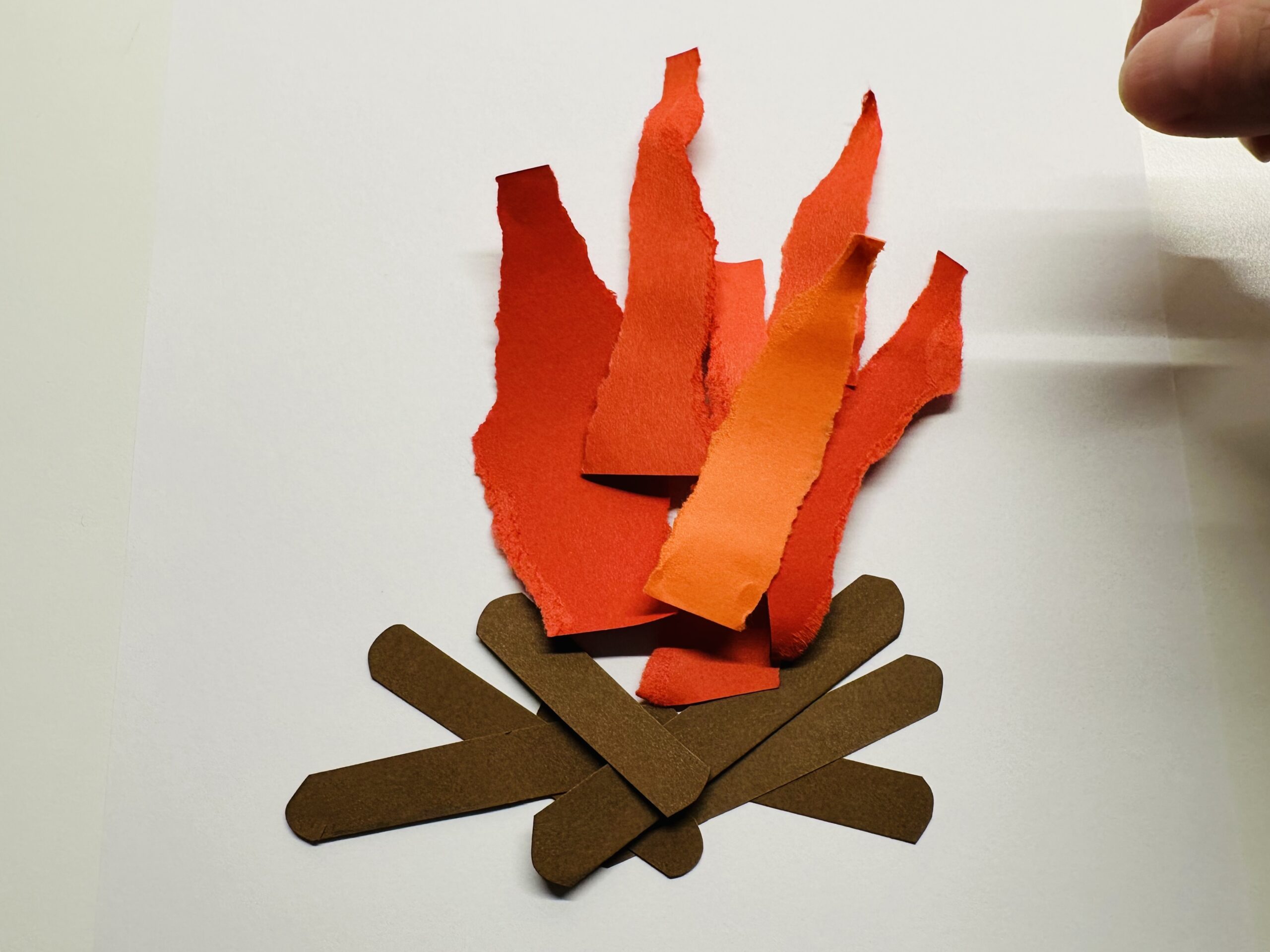 Bild zum Schritt 12 für das Bastel- und DIY-Abenteuer für Kinder: 'Legt auf die roten Flammen ein paar orangefarbene Flammen.'