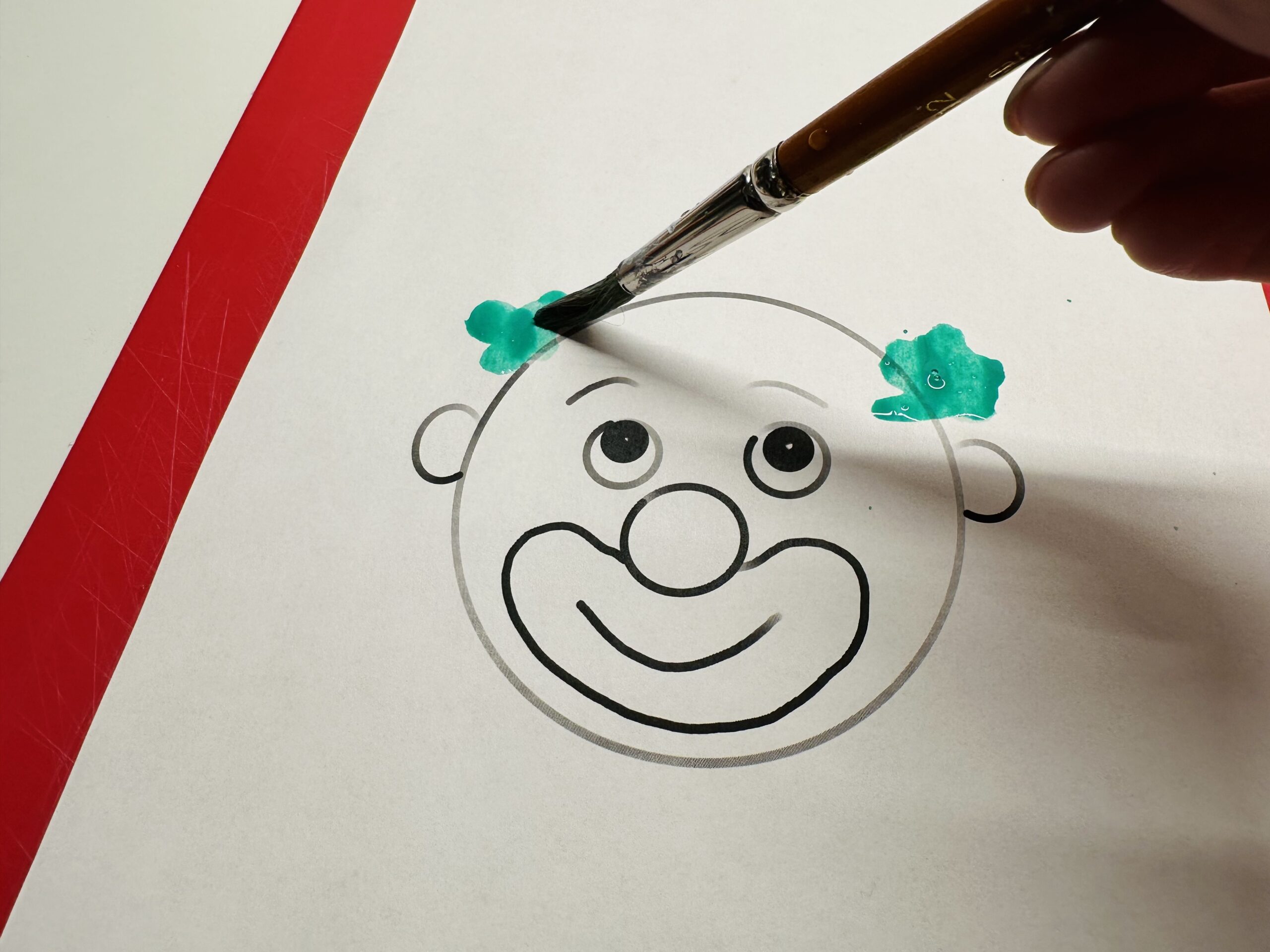 Bild zum Schritt 4 für das Bastel- und DIY-Abenteuer für Kinder: 'Malt mit dem Pinsel zwei Farbtupfer an den Clownkopf.'