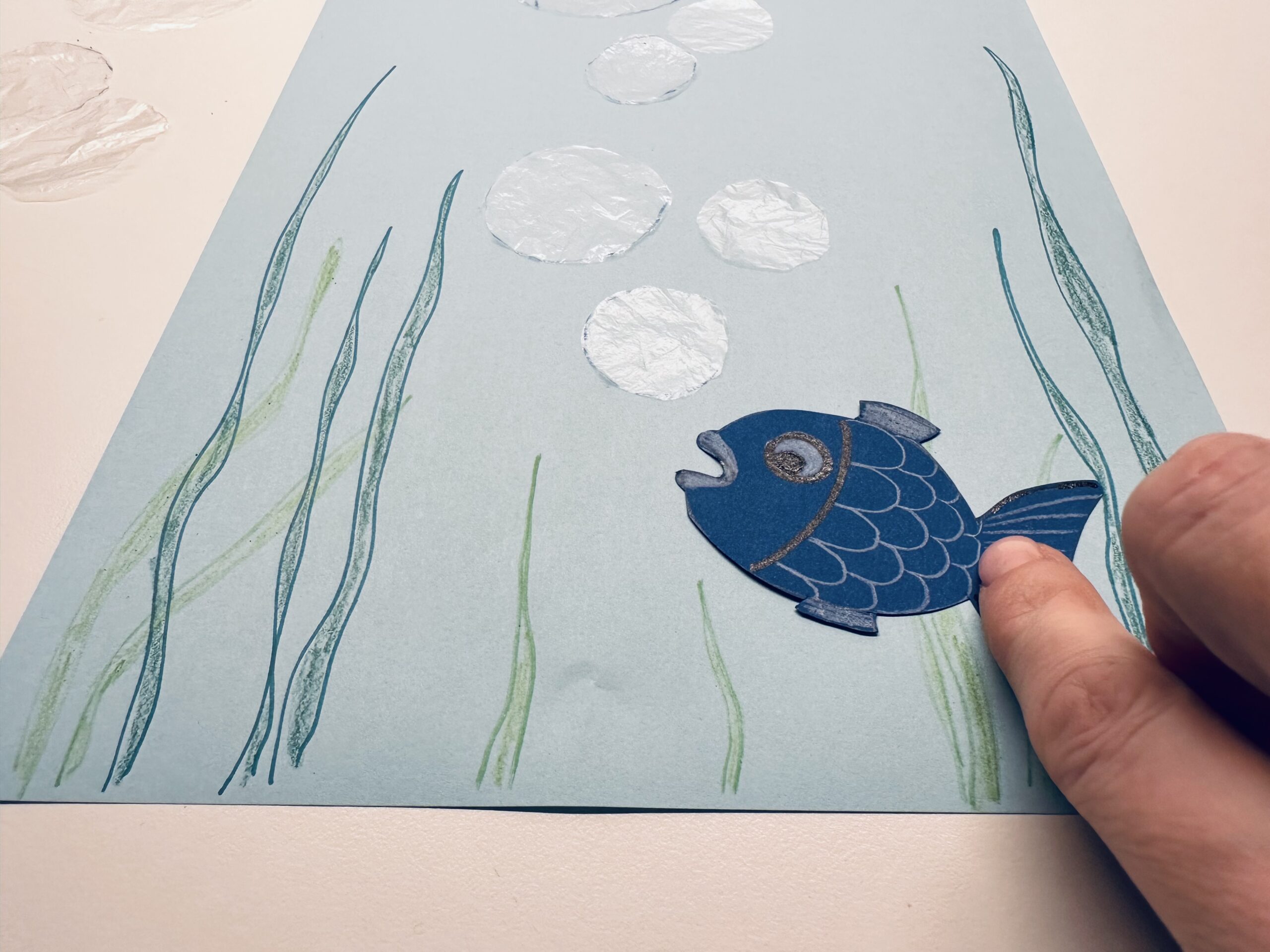 Bild zum Schritt 15 für das Bastel- und DIY-Abenteuer für Kinder: 'Klebt dann auch den Fisch auf das Blatt.'
