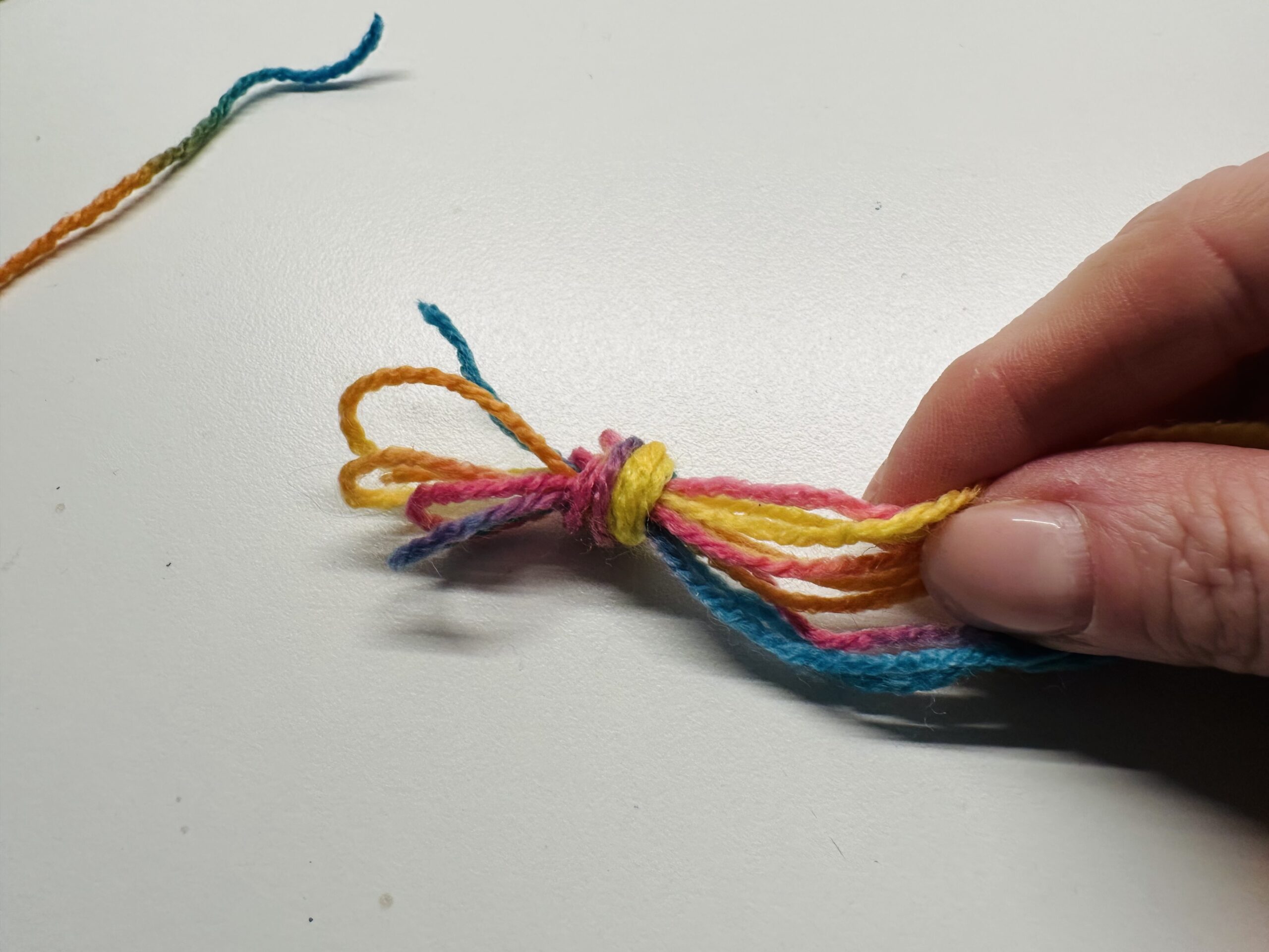 Bild zum Schritt 5 für das Bastel- und DIY-Abenteuer für Kinder: 'Macht einen Knoten am Ende aller Fäden.'