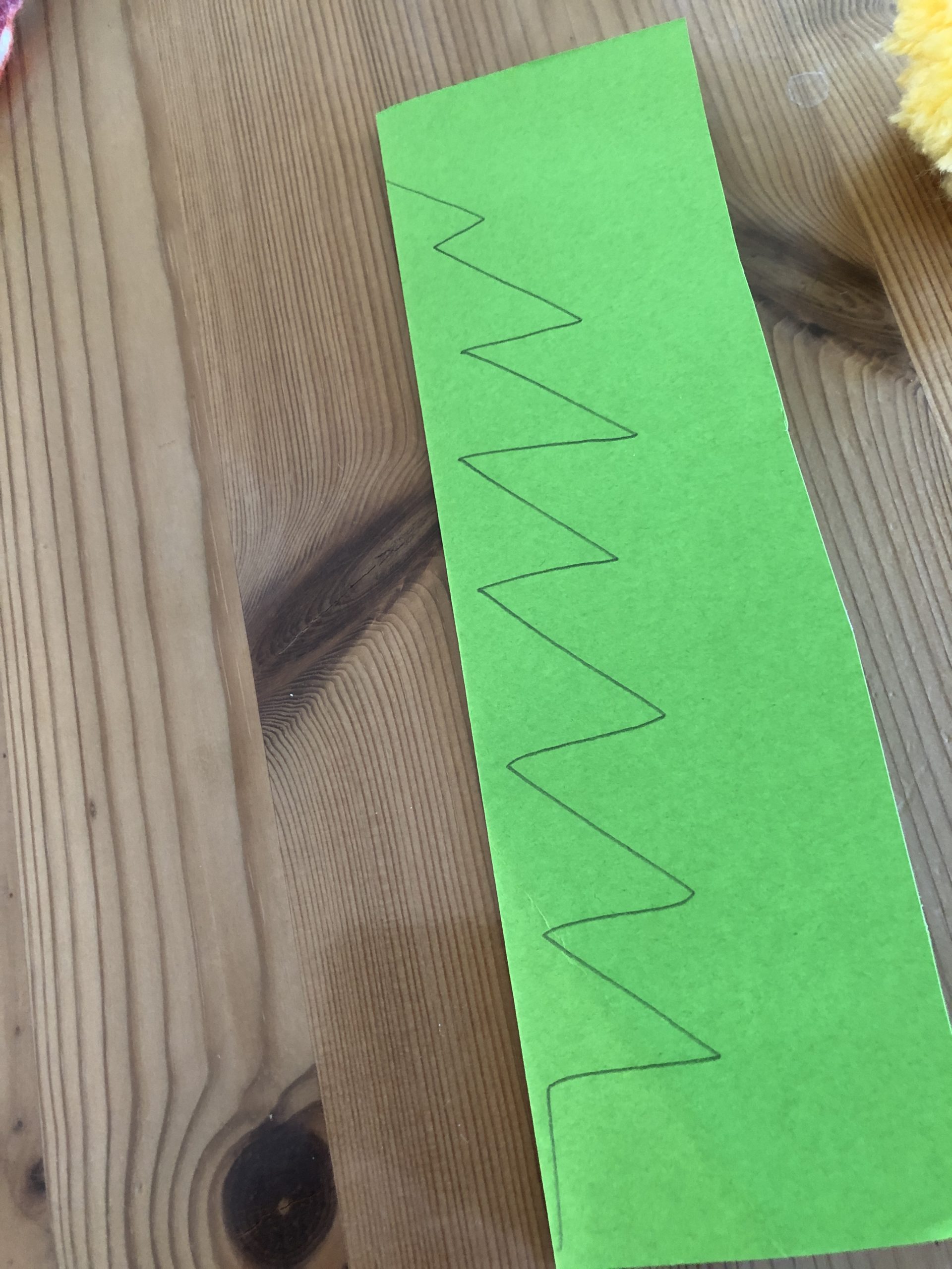 Bild zum Schritt 3 für das Bastel- und DIY-Abenteuer für Kinder: 'Auf das gefaltete Papier Zick-Zack-Muster aufmalen in Form eines „halben“...'