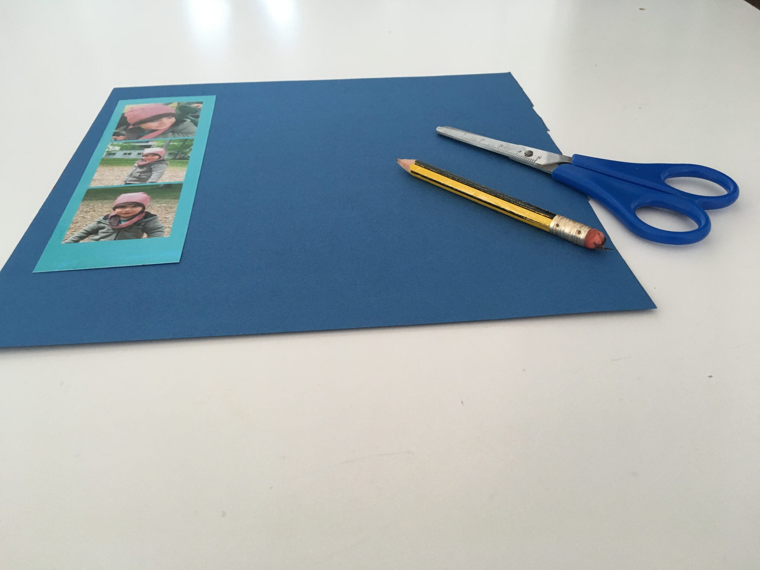 Bild zum Schritt 2 für das Bastel- und DIY-Abenteuer für Kinder: 'Bildstreifen auf das Tonpapier legen und mit etwas Rand das...'