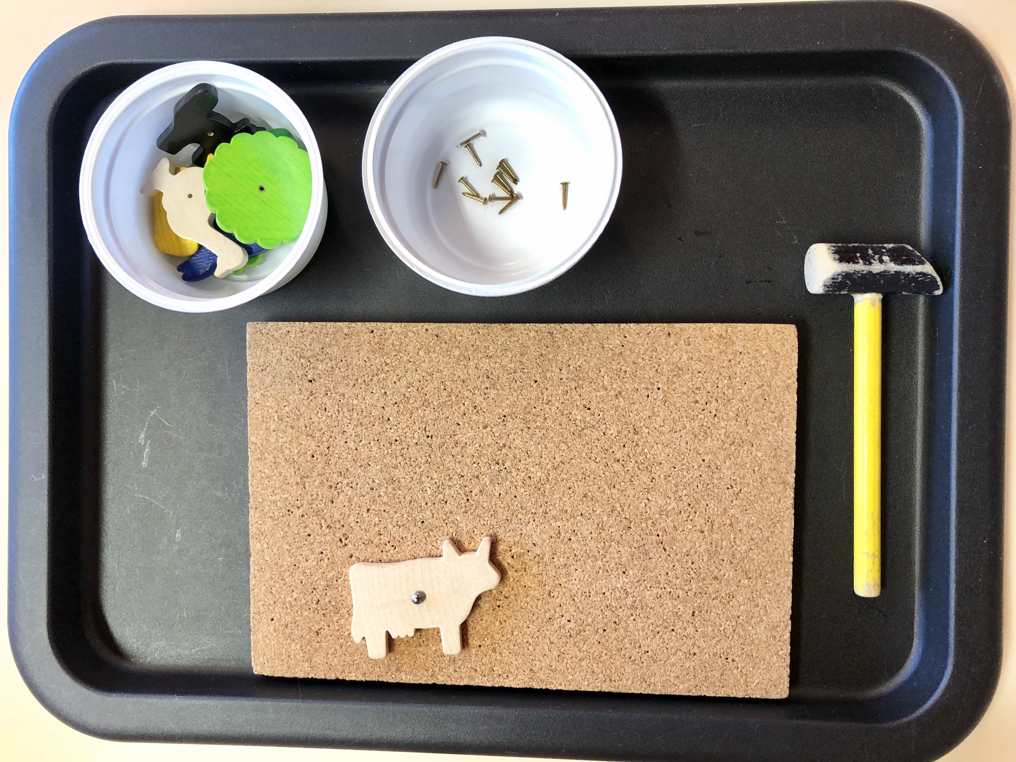 Bild zum Schritt 2 für das Bastel- und DIY-Abenteuer für Kinder: 'Tablett mit Korkplatte, Hammer und Schälchen mit Holzfiguren und Nägeln...'