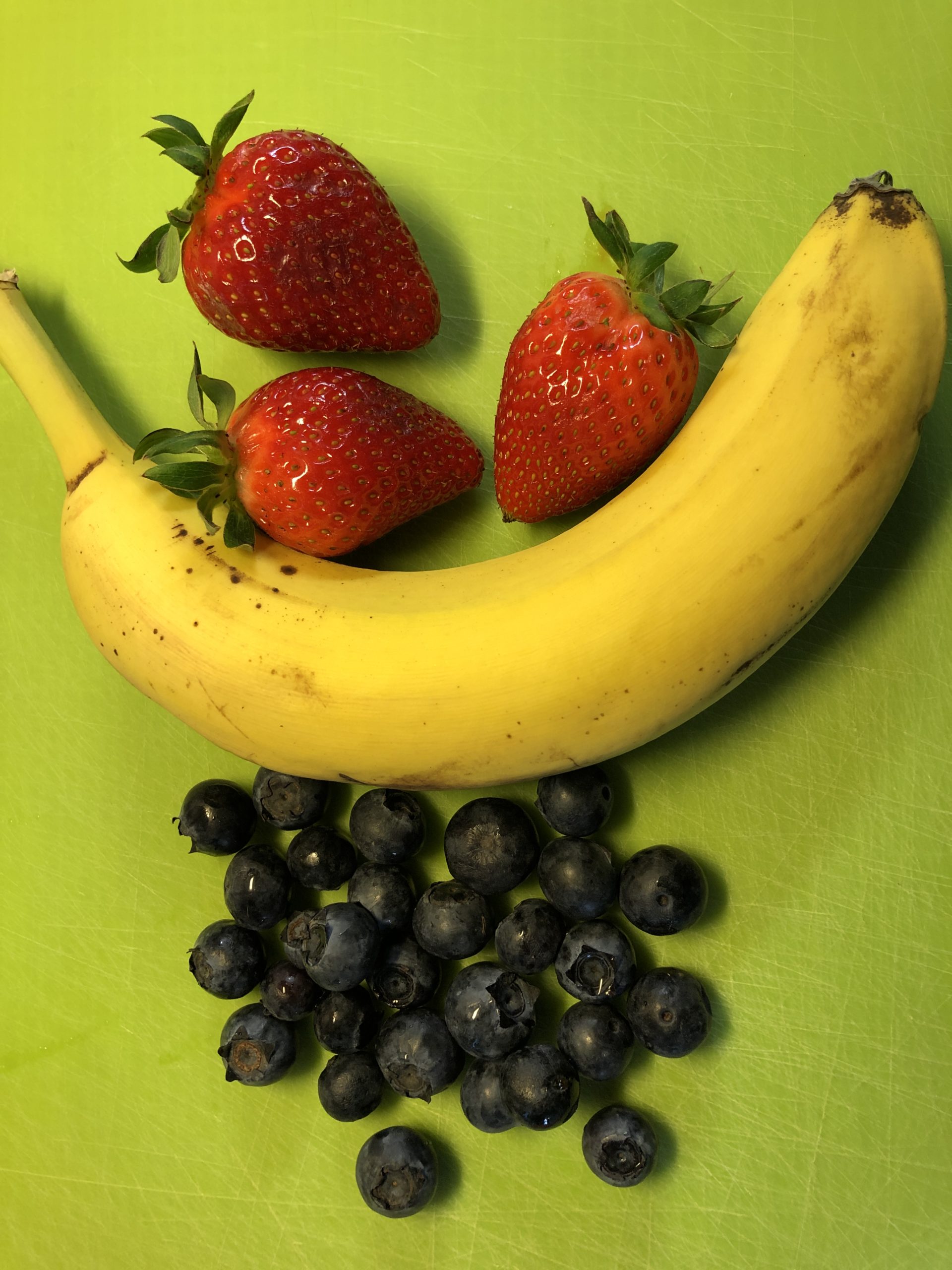 Bild zum Schritt 1 für die Kinder-Beschäftigung: 'Erdbeeren und Heidelbeeren waschen, Stile und Blätter entfernen. Banane schälen.'