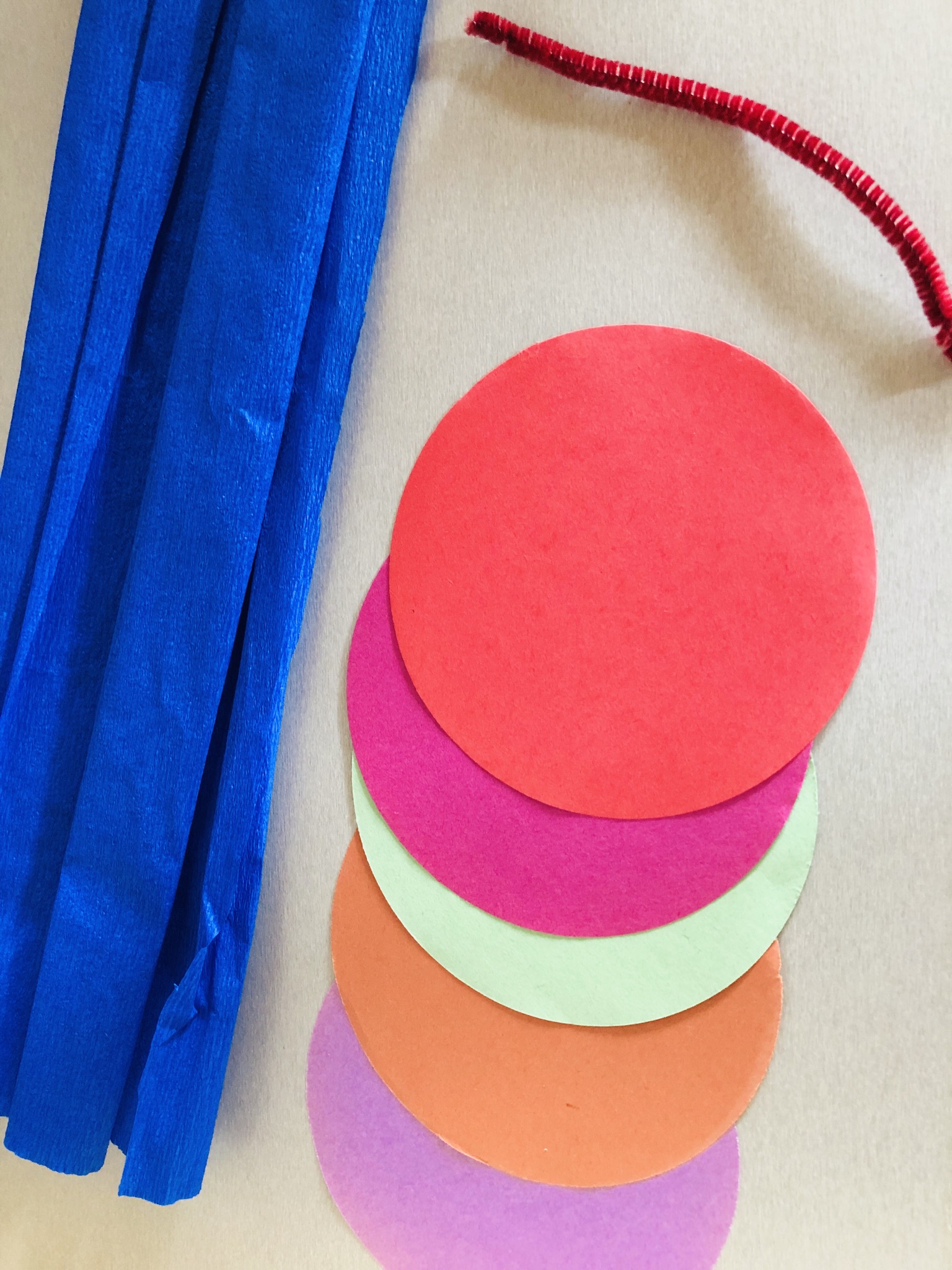 Bild zum Schritt 1 für das Bastel- und DIY-Abenteuer für Kinder: 'Runde Faltpapiere in verschiedenen Farben und Pfeifenputzer bereit legen.'