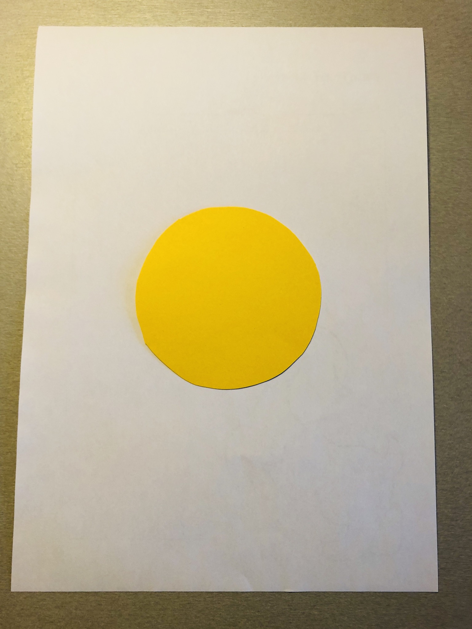 Bild zum Schritt 3 für die Kinder-Beschäftigung: 'Legt den gelben Tonpapier-Kreis auf das weiße DIN A4 Blatt.'
