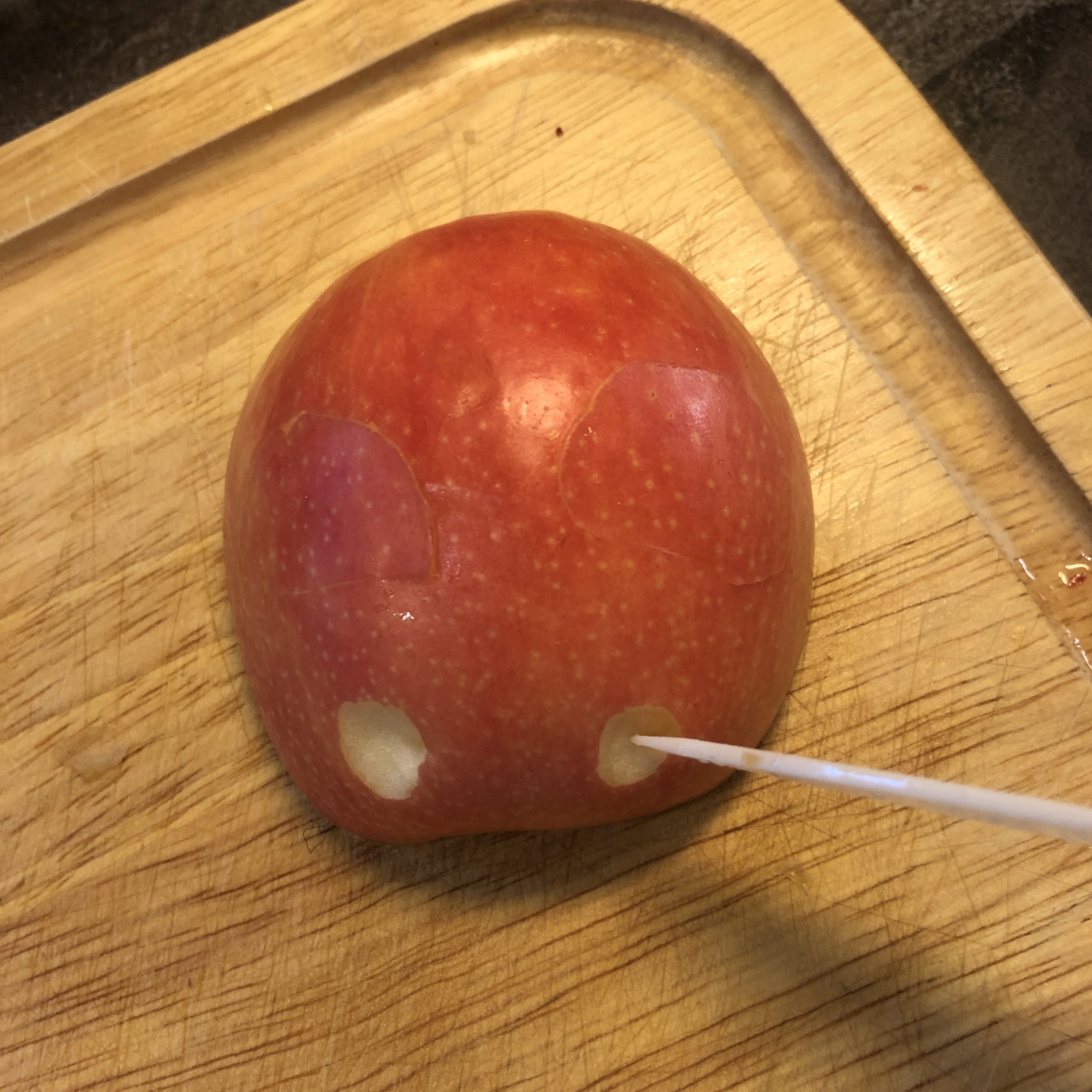 Bild zum Schritt 6 für das Bastel- und DIY-Abenteuer für Kinder: 'Mit der Messerspitze werden an einer Apfelhälfte zwei kleine „Augen“...'