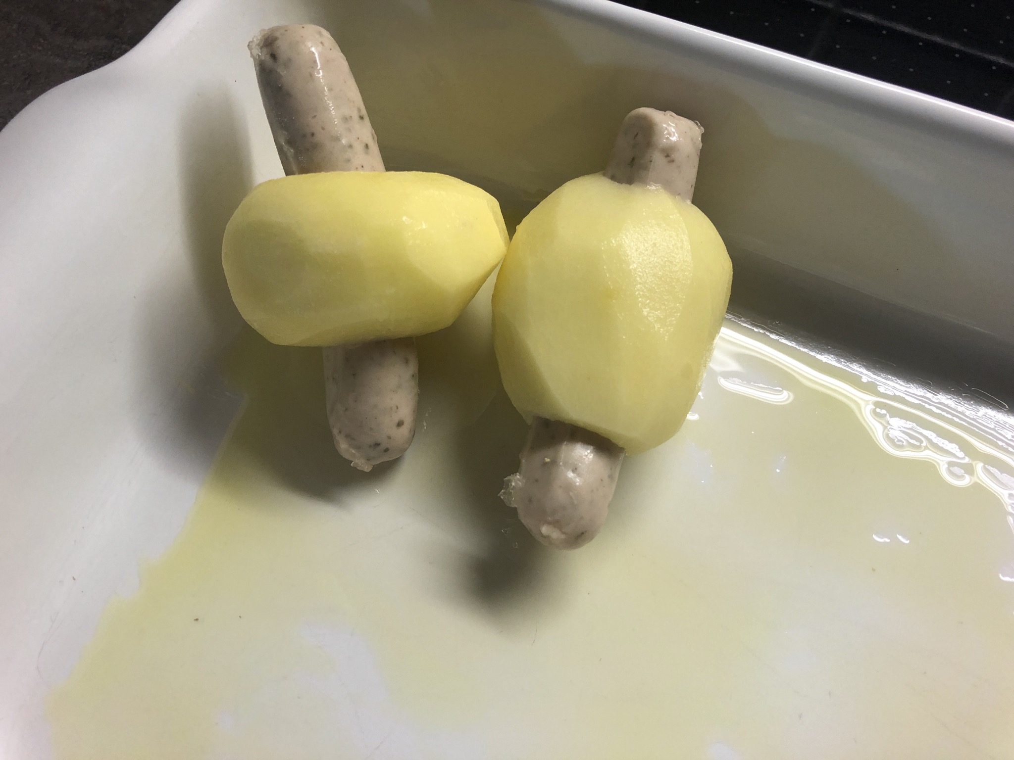 2. Bild zum Schritt 9 für das Bastel- und DIY-Abenteuer für Kinder: 'Eine Auflaufform mit Olivenöl einpinseln und die Kartoffel-Würstchen hineinlegen.'