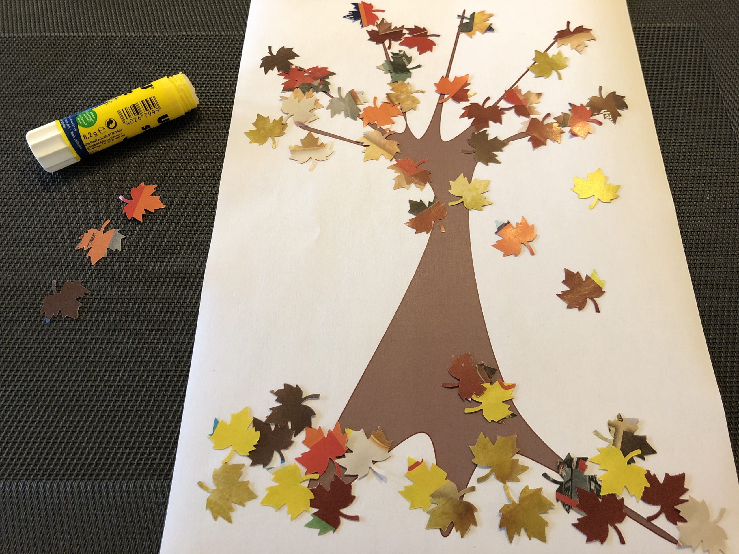 Bild zum Schritt 7 für die Kinder-Beschäftigung: 'Klebt bunte Blätter in die Krone des Baumes und am...'