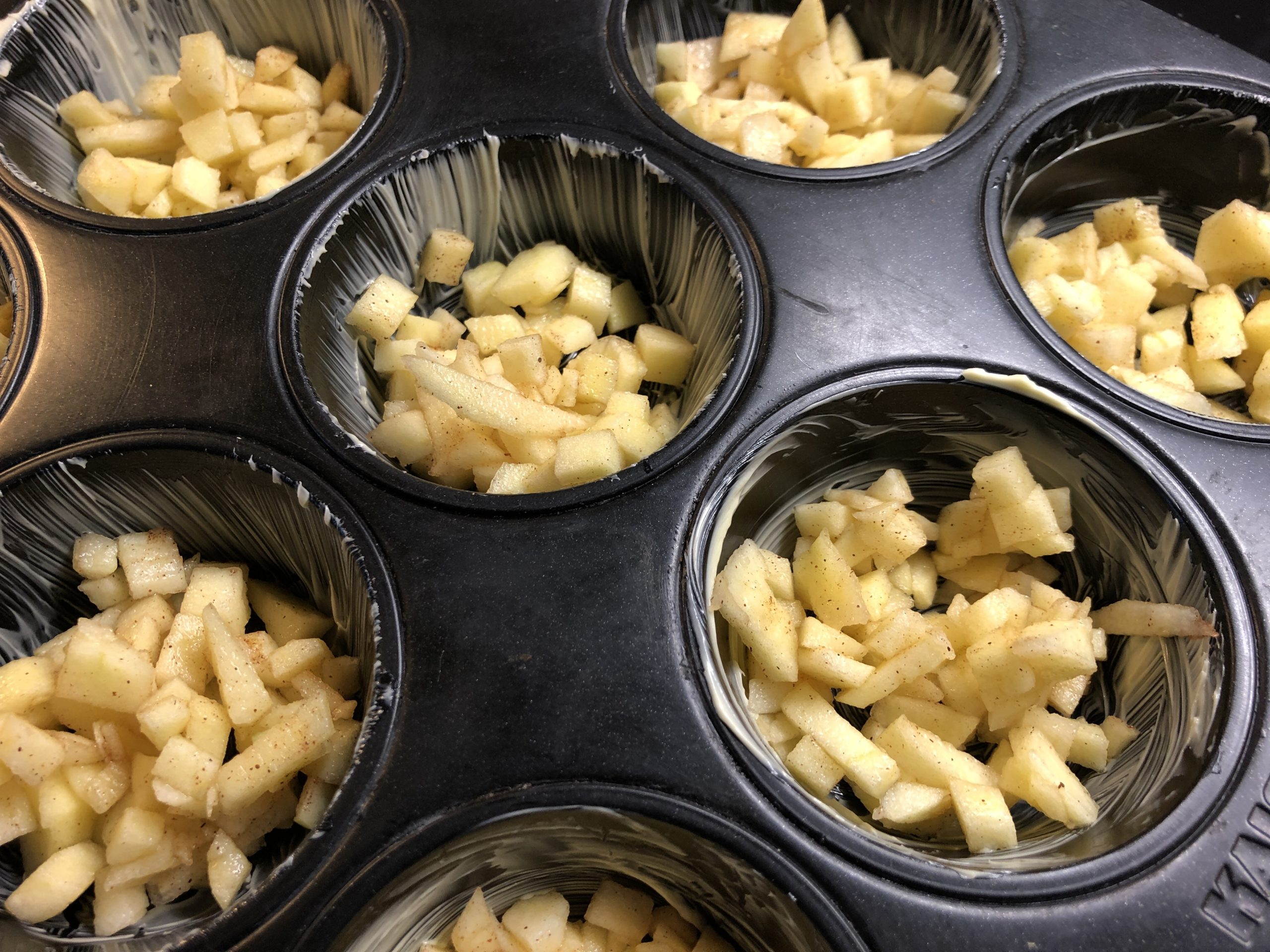Bild zum Schritt 21 für die Kinder-Beschäftigung: 'Zuerst wird die Apfelmasse in die Muffin-Formen gefüllt.'